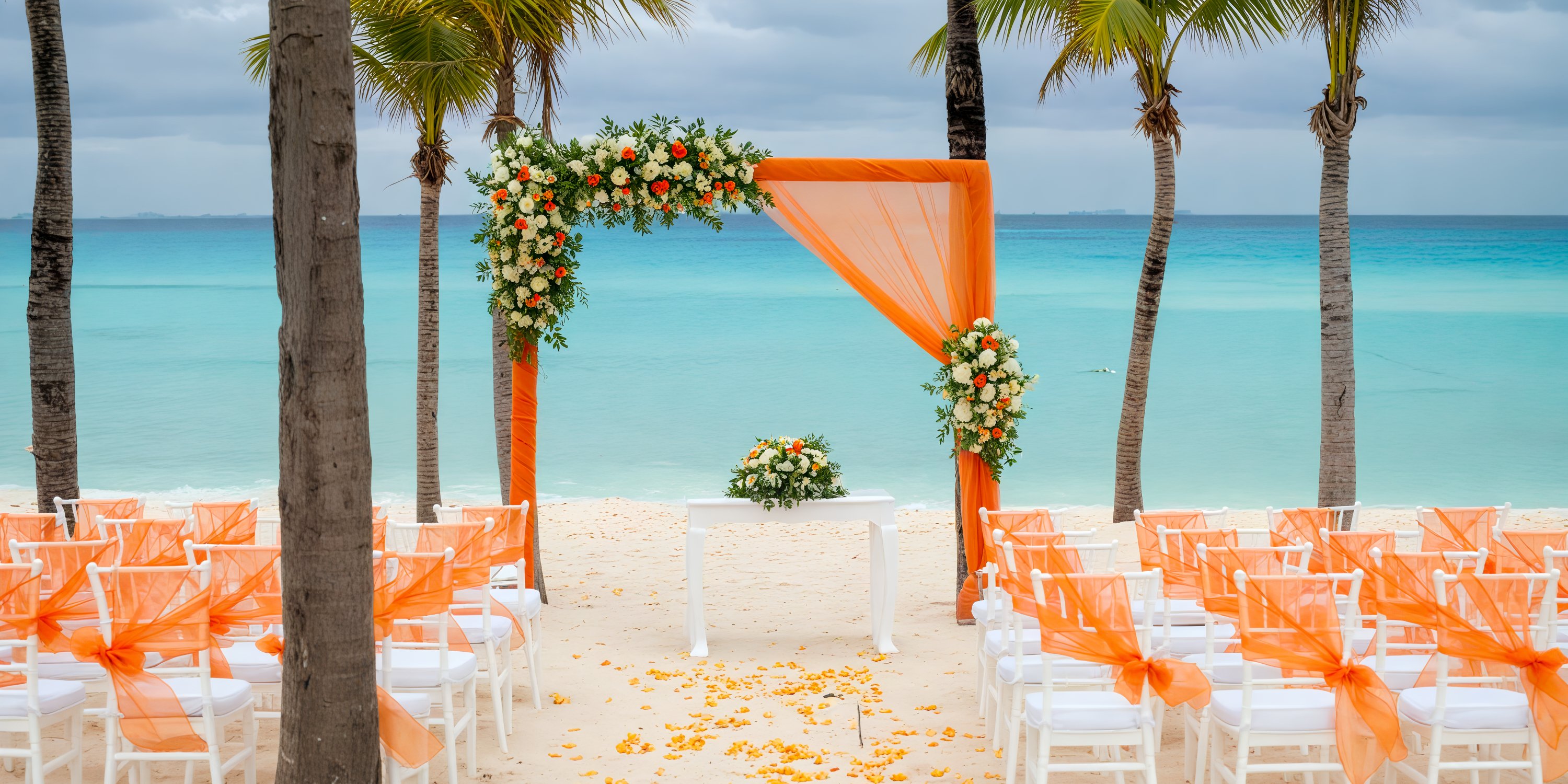 Beautiful oceanfront destination wedding setup featuring elegant orange and white décor at Hotel Riu Palace Riviera Maya.
