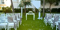 A beautiful destination wedding ceremony setup at Hotel Riu Palace Riviera Maya, featuring elegant white chairs and stunning floral décor.