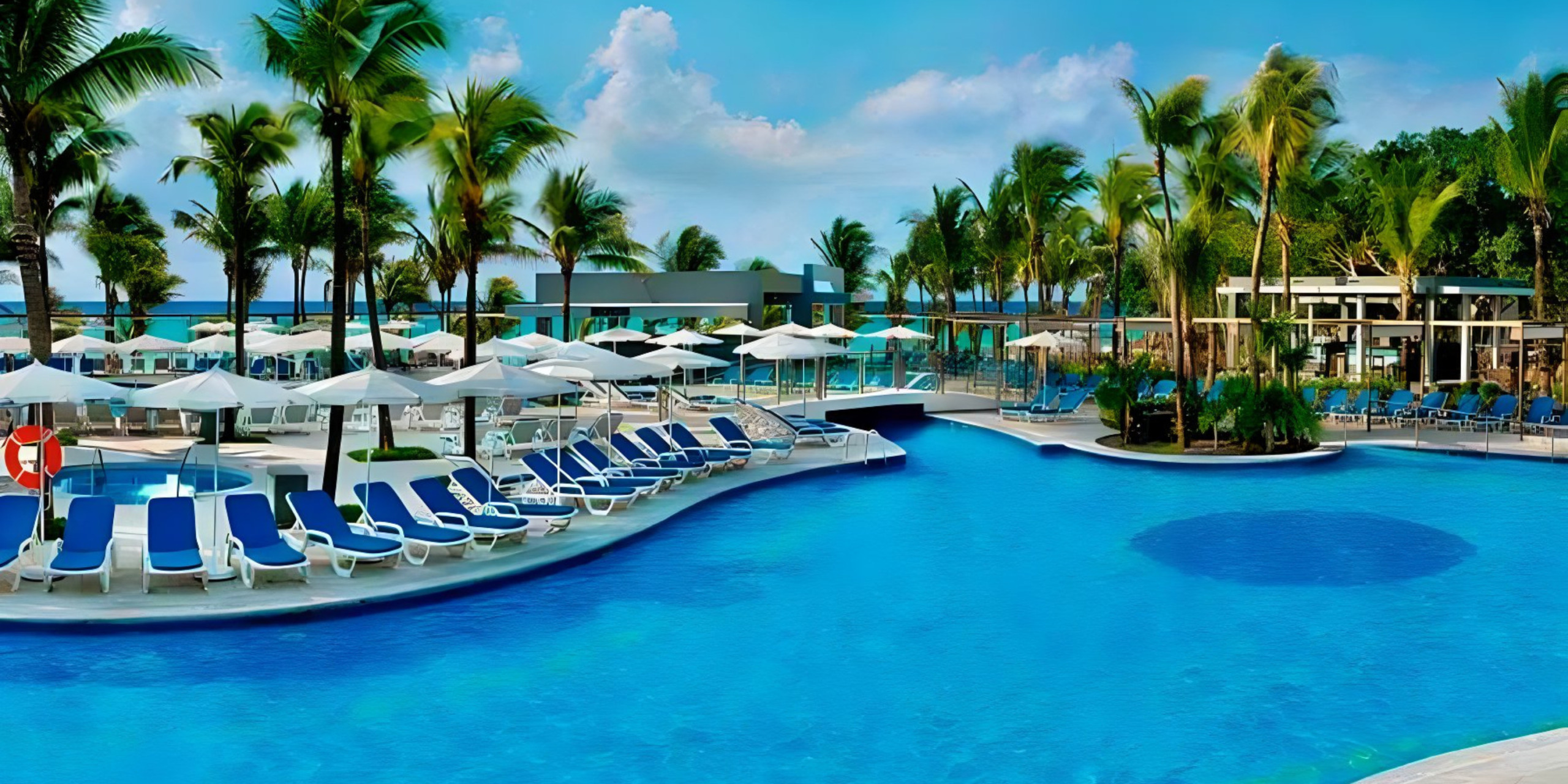 A large swimming pool with lounge chairs and umbrellas perfect for a destination wedding at Hotel Riu Yucatan.