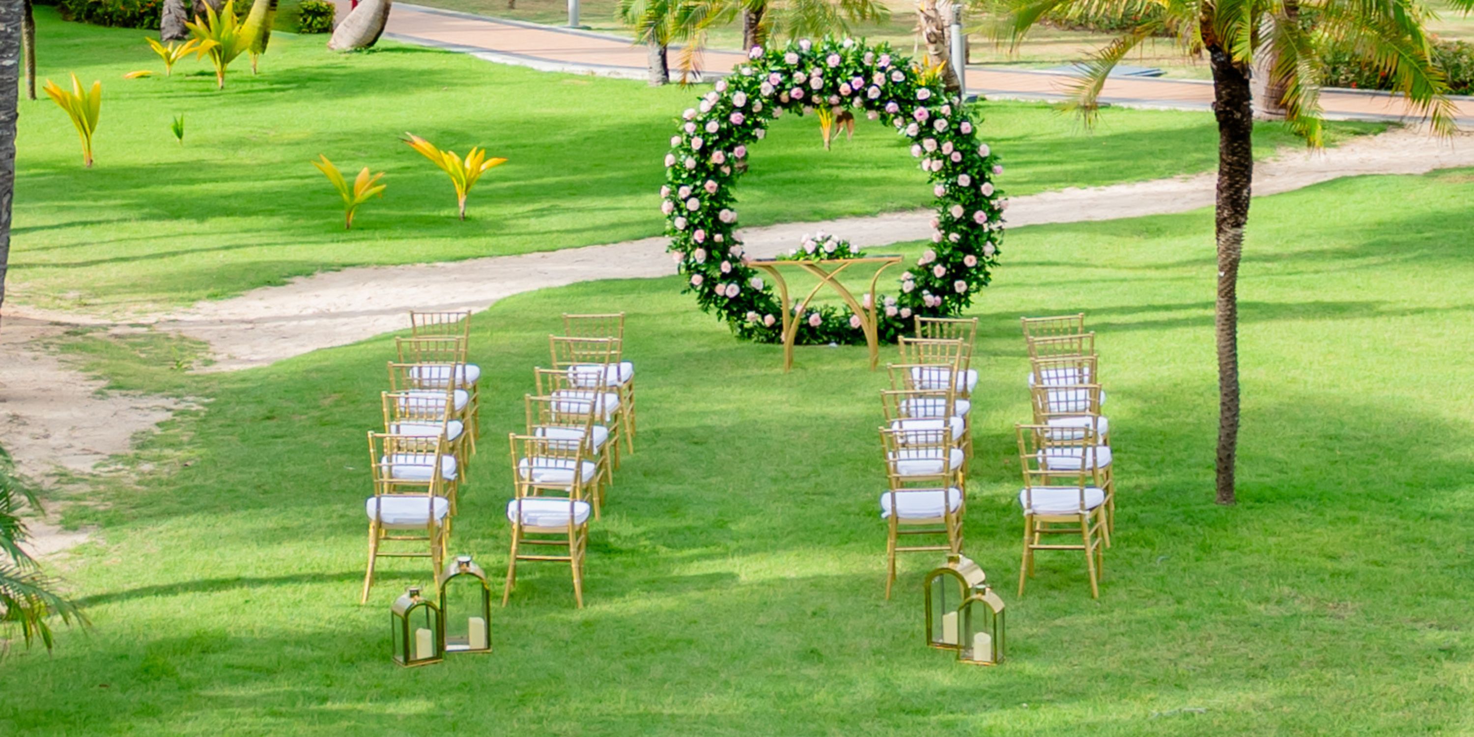Destination wedding ceremony at Hotel Riu Bambu, featuring gold chairs and a floral circular arch outdoors.