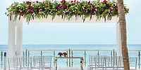 Elegant destination wedding setup at Hotel Riu Cancun, featuring floral decor, chairs, and ocean views.
