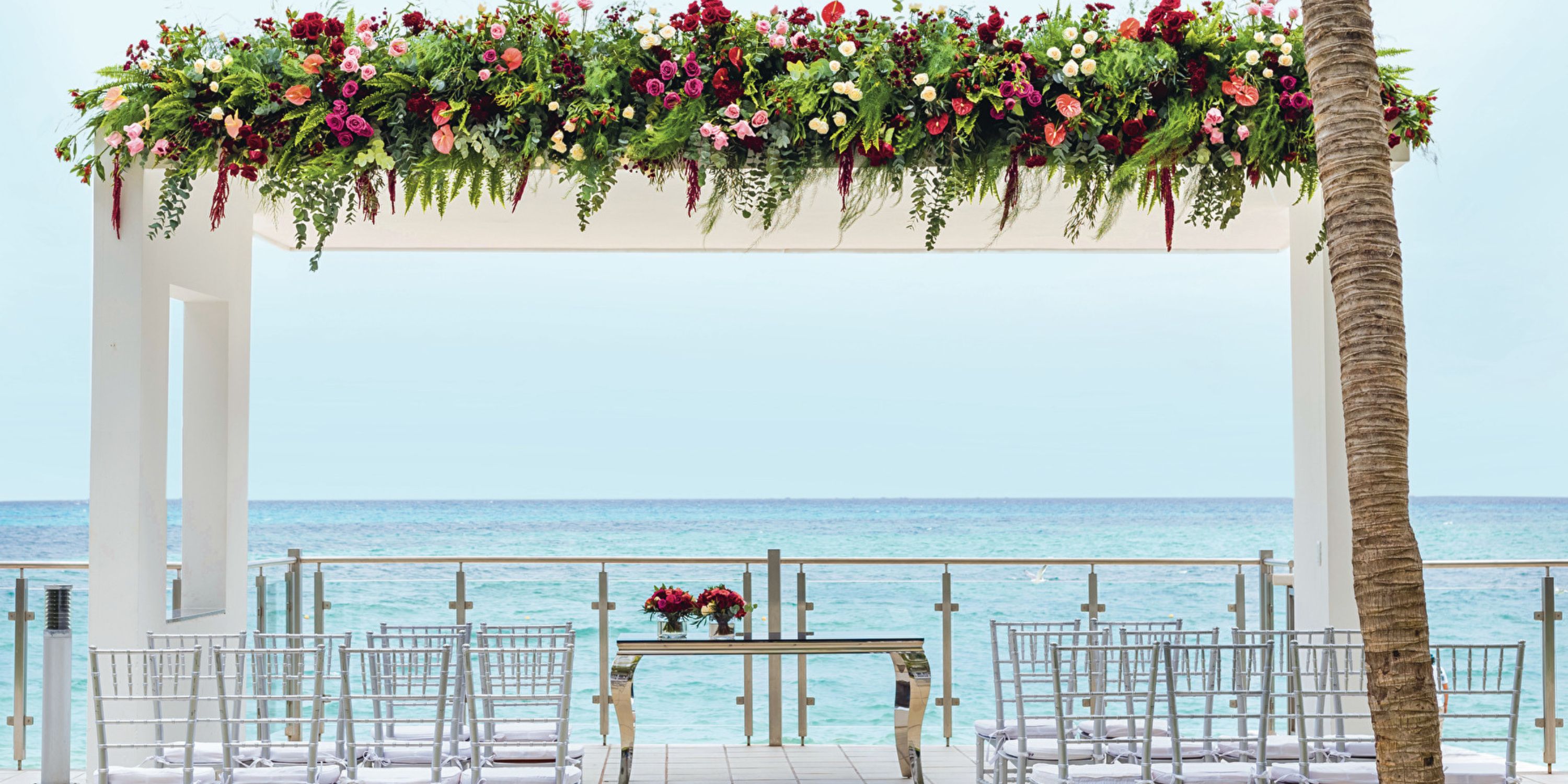 Elegant destination wedding setup at Hotel Riu Cancun, featuring floral decor, chairs, and ocean views.