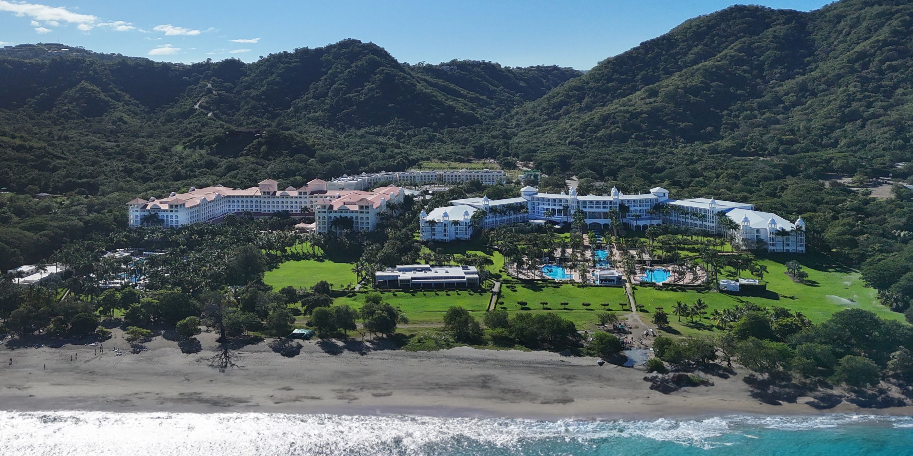 Hotel Riu Guanacaste: A stunning beachfront resort with pools and lush gardens, nestled among green hills—an ideal setting for a romantic destination wedding.