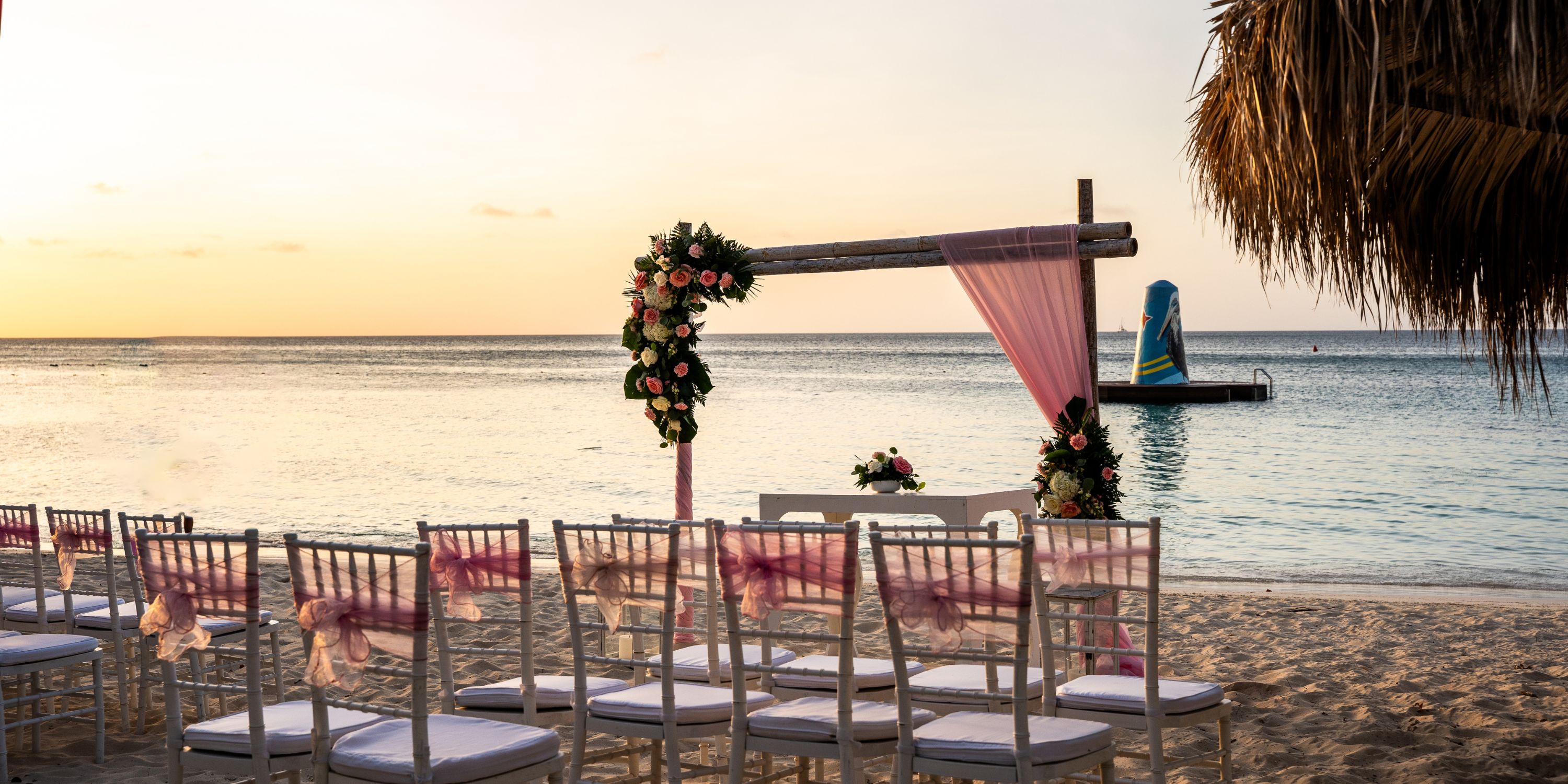 Chairs arranged in rows face a floral arch on the beach for a destination wedding at Hotel Riu Palace Antillas.