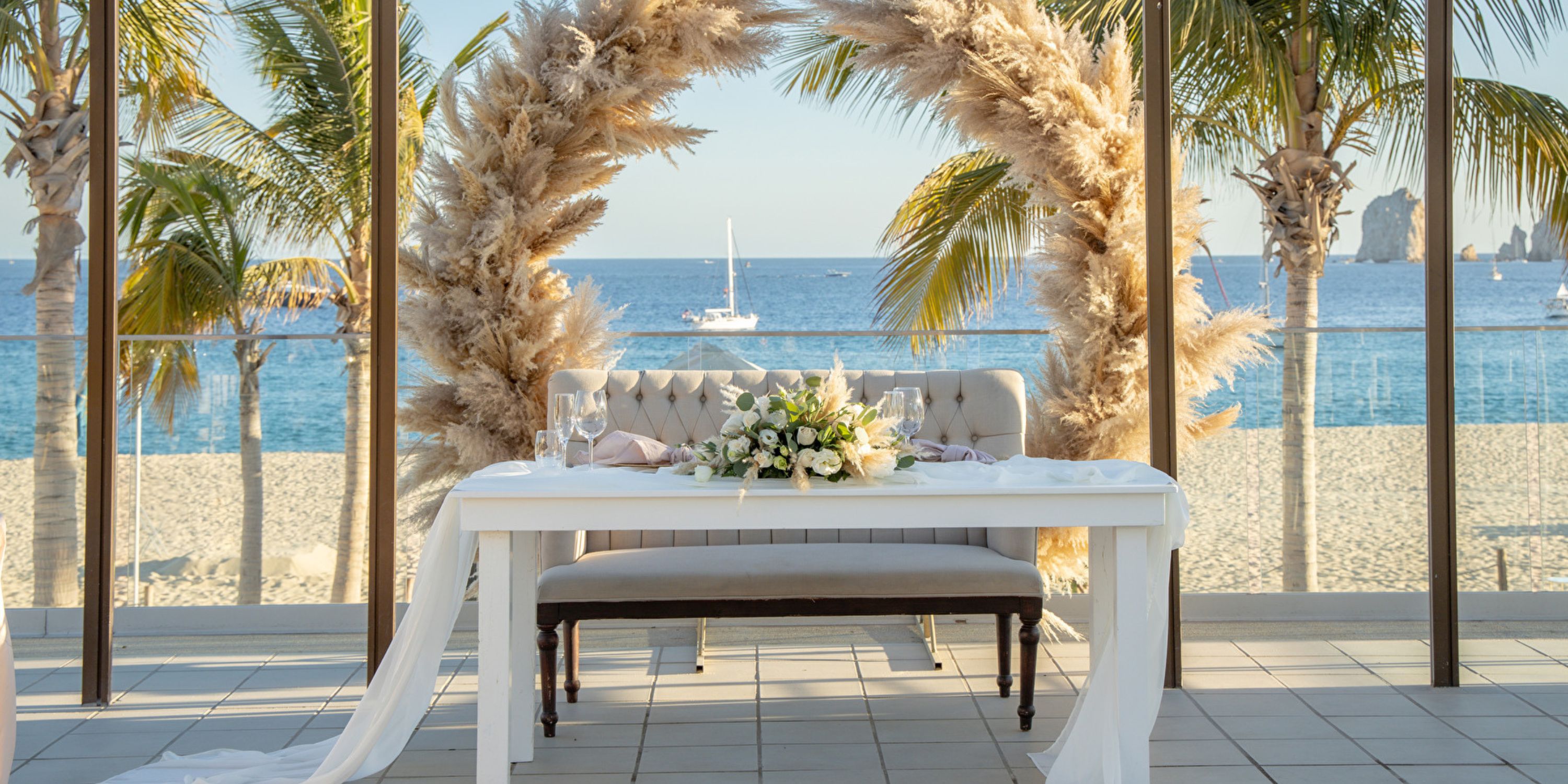 A destination wedding table at Hotel Riu Palace Baja California, with a floral arch and ocean view.