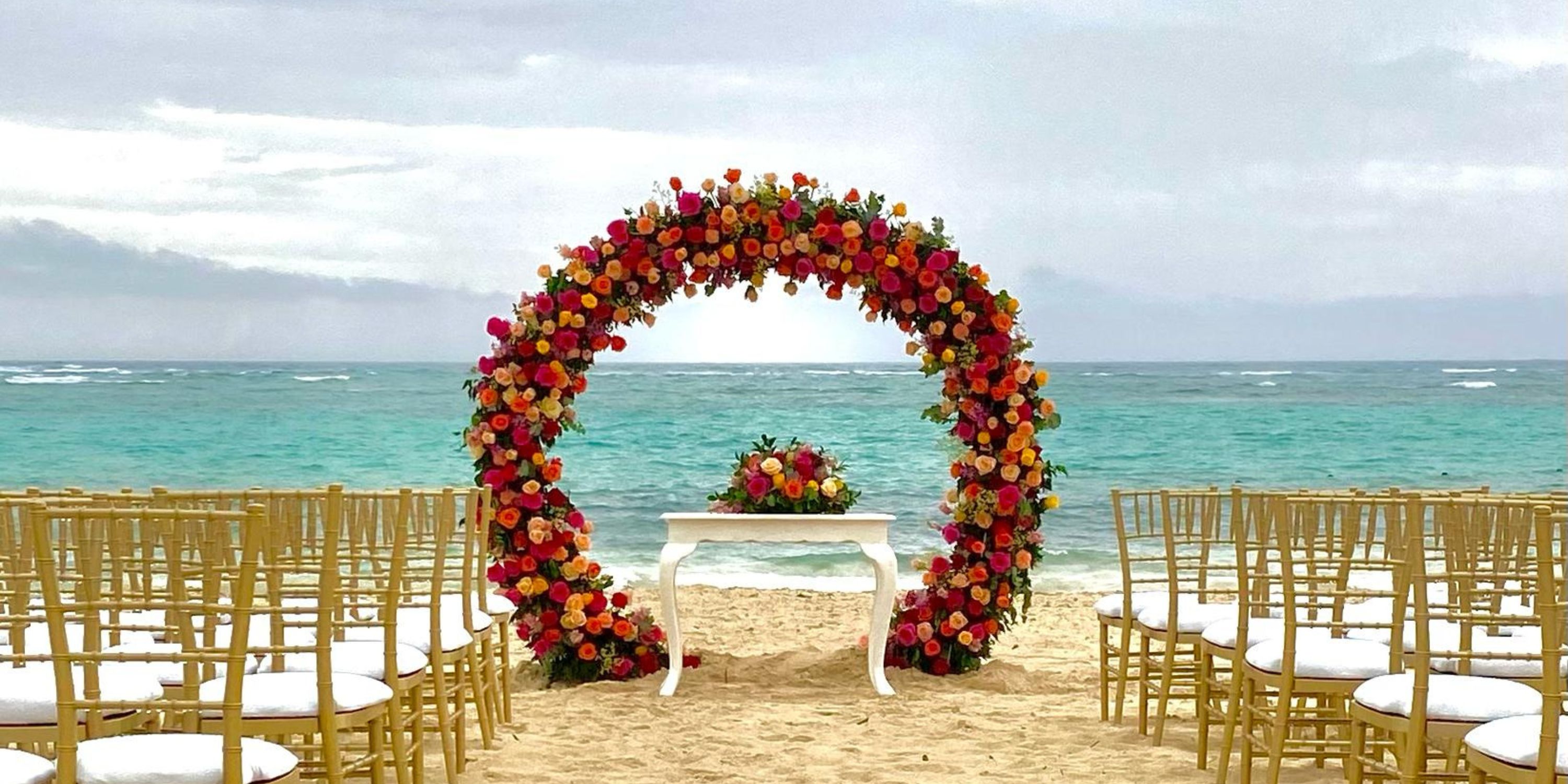 Destination wedding setup on the beach with gold chairs and a floral arch at Hotel Riu Palace Bavaro.