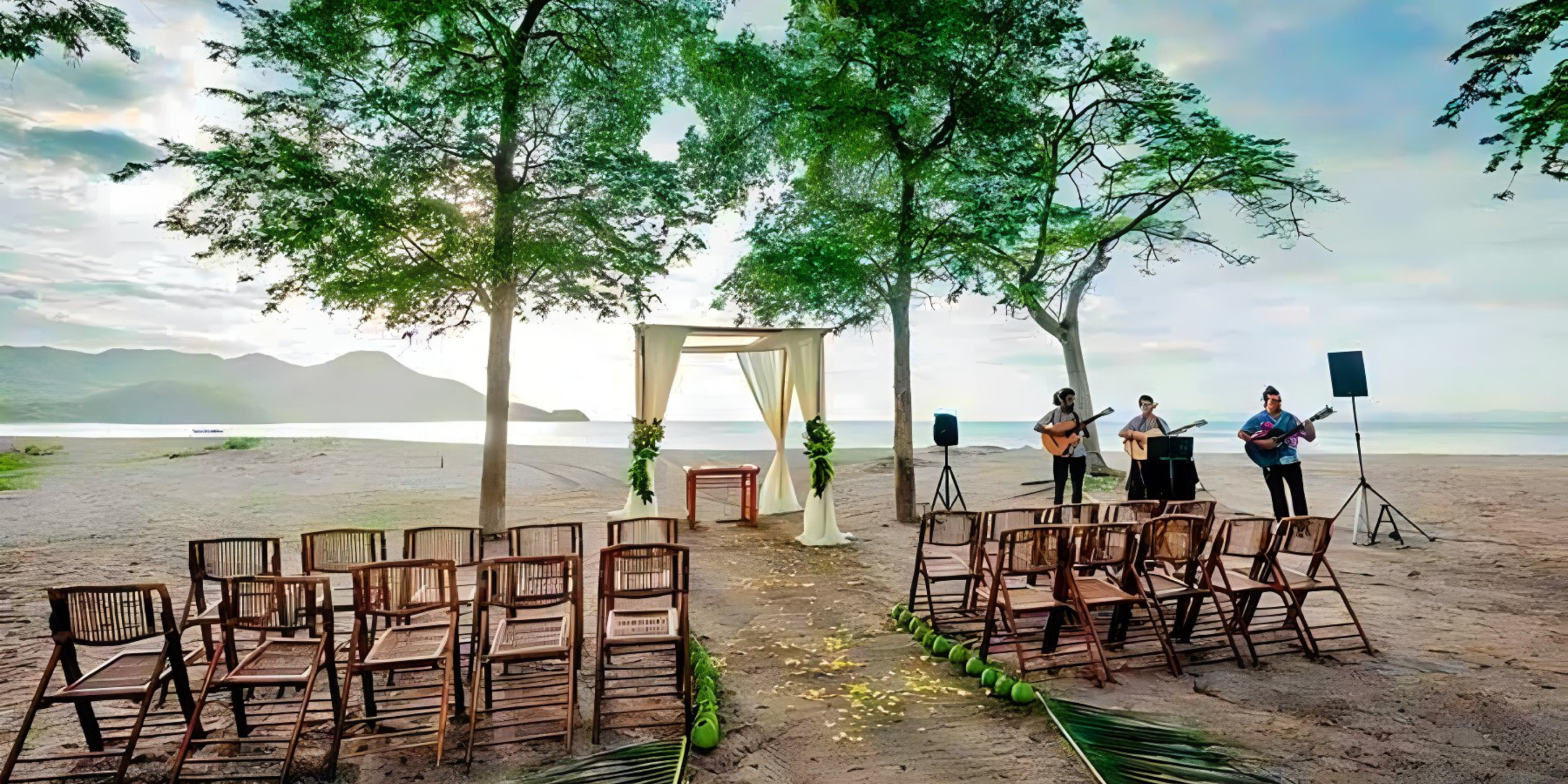 A Destify wedding ceremony set up on a beach with chairs and trees.