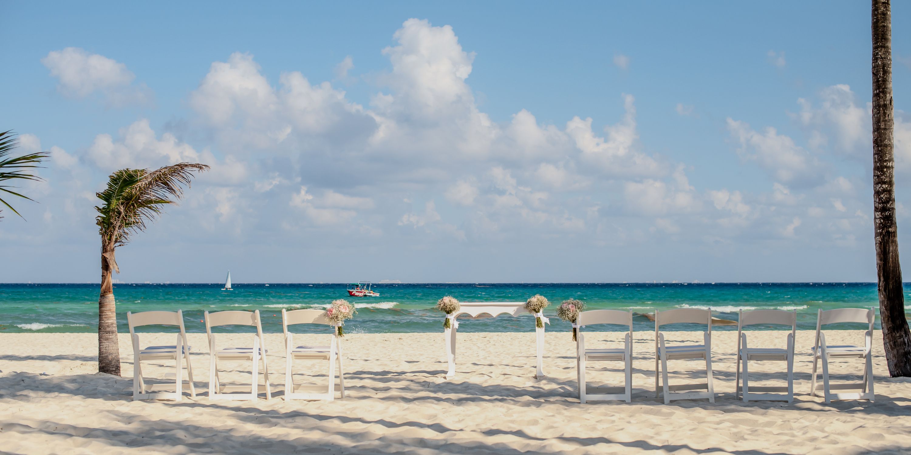 White chairs arranged for a destination wedding at Hotel Riu Palace Mexico, overlooking the ocean.