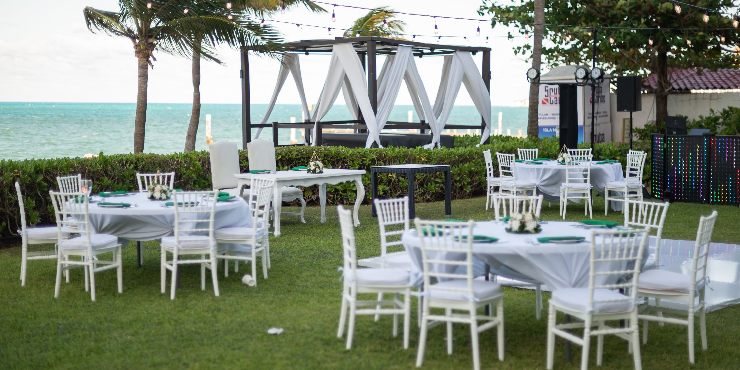 Destination wedding setup at Hotel Riu Palace Peninsula, featuring white tables and chairs beside the ocean.