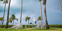 Destination wedding ceremony at Hotel Riu Palace Peninsula featuring white chairs and a floral wedding arch.
