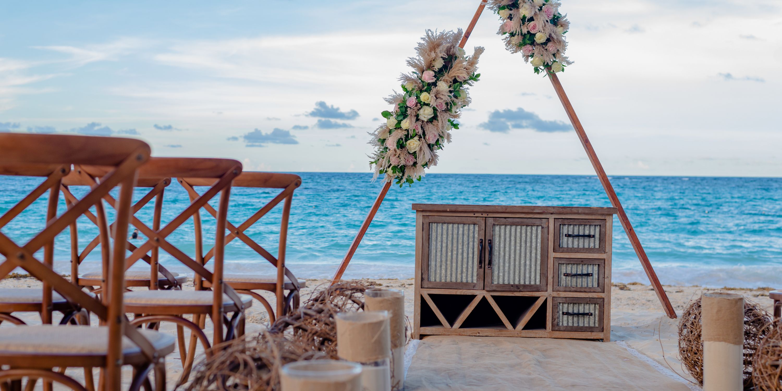 Floral-adorned wooden arch for a destination wedding on the beach at Hotel Riu Palace Punta Cana.