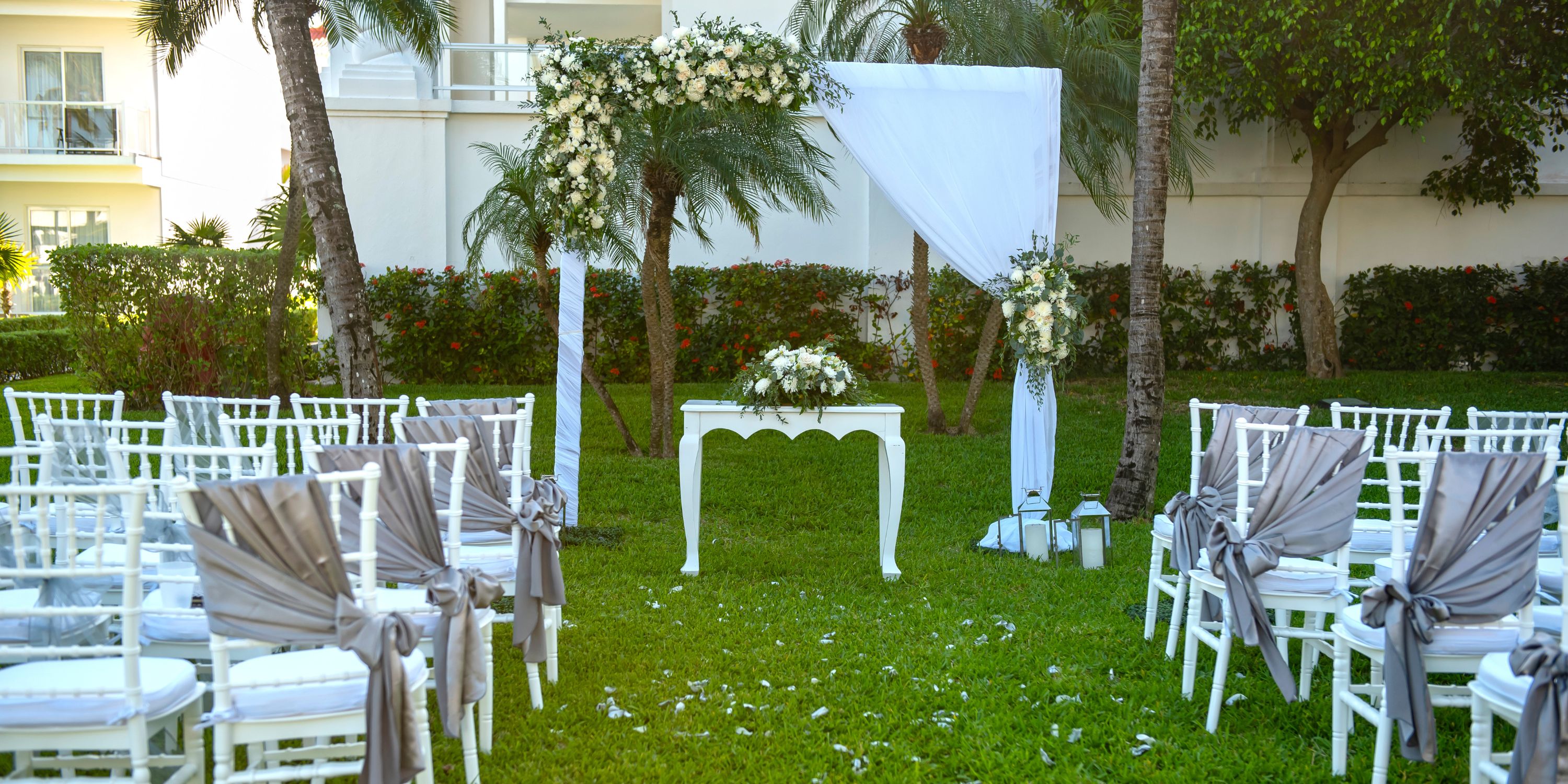 Destination wedding setup at Hotel Riu Palace Riviera Maya with white chairs, arch, and decorated table.