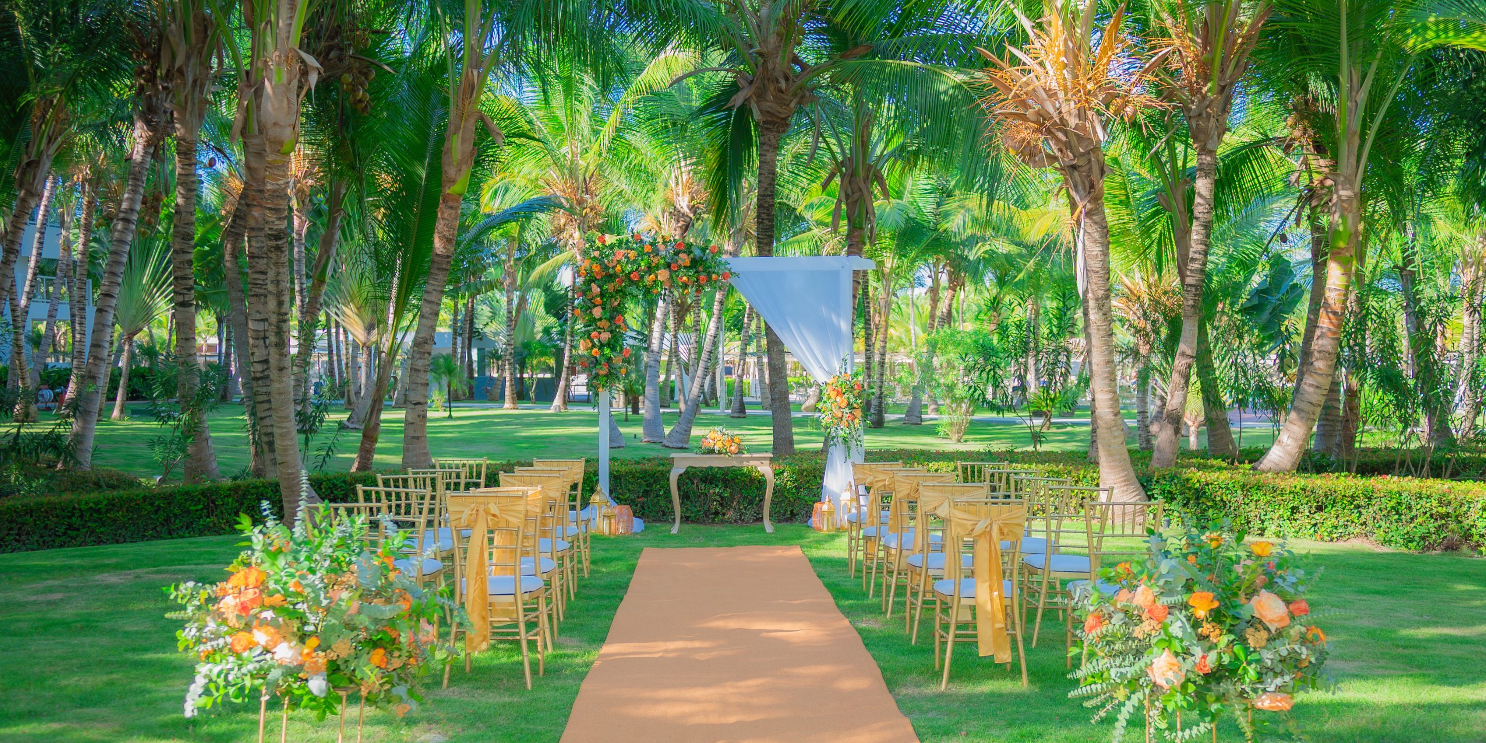 Hotel Riu Republica destination wedding setup with chairs, florals, and an arch beneath palm trees.