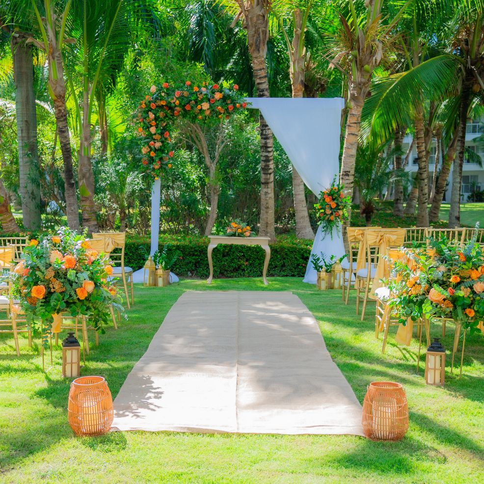 Destination wedding ceremony arrangement featuring floral accents, elegant chairs, and a draped archway.