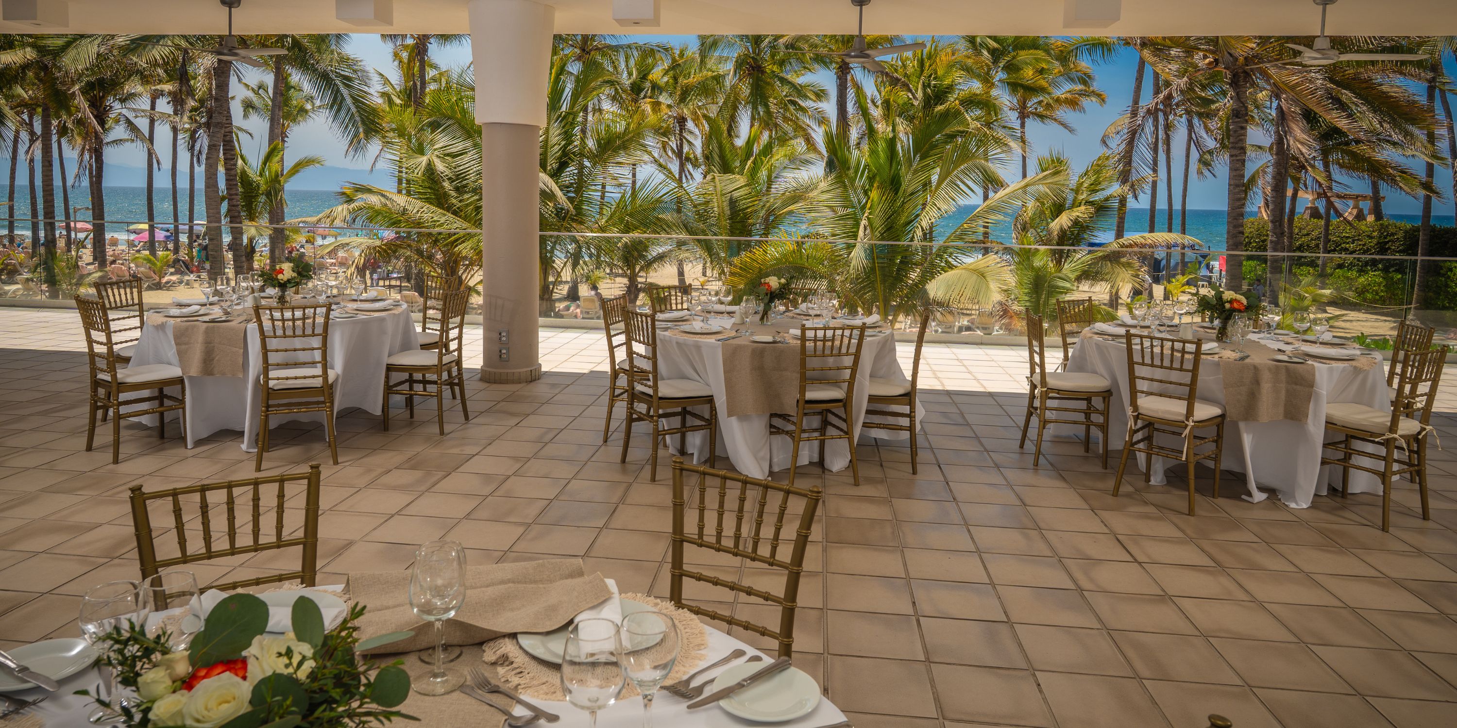 Destination wedding setup with round tables at Hotel Riu Vallarta, overlooking palms and ocean views.