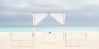 Destination wedding arch and chairs arranged on sandy beach at Hotel Riu Yucatan with ocean views.