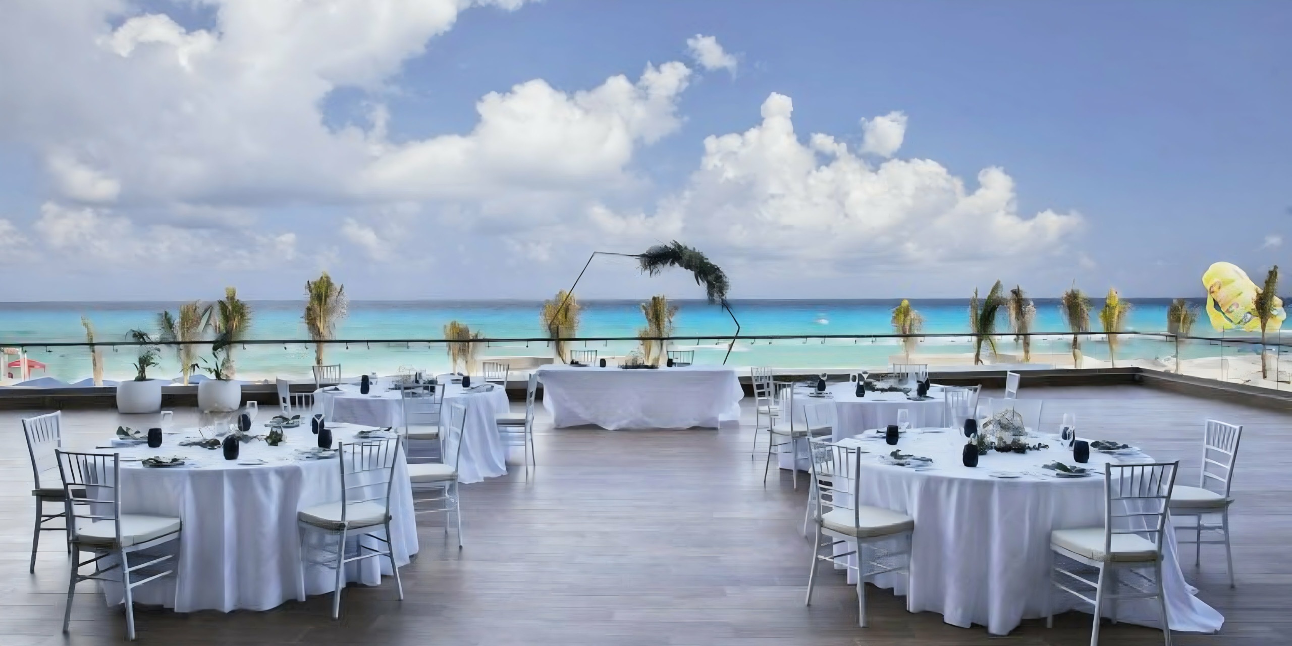 A wedding reception set up on a balcony overlooking the ocean.