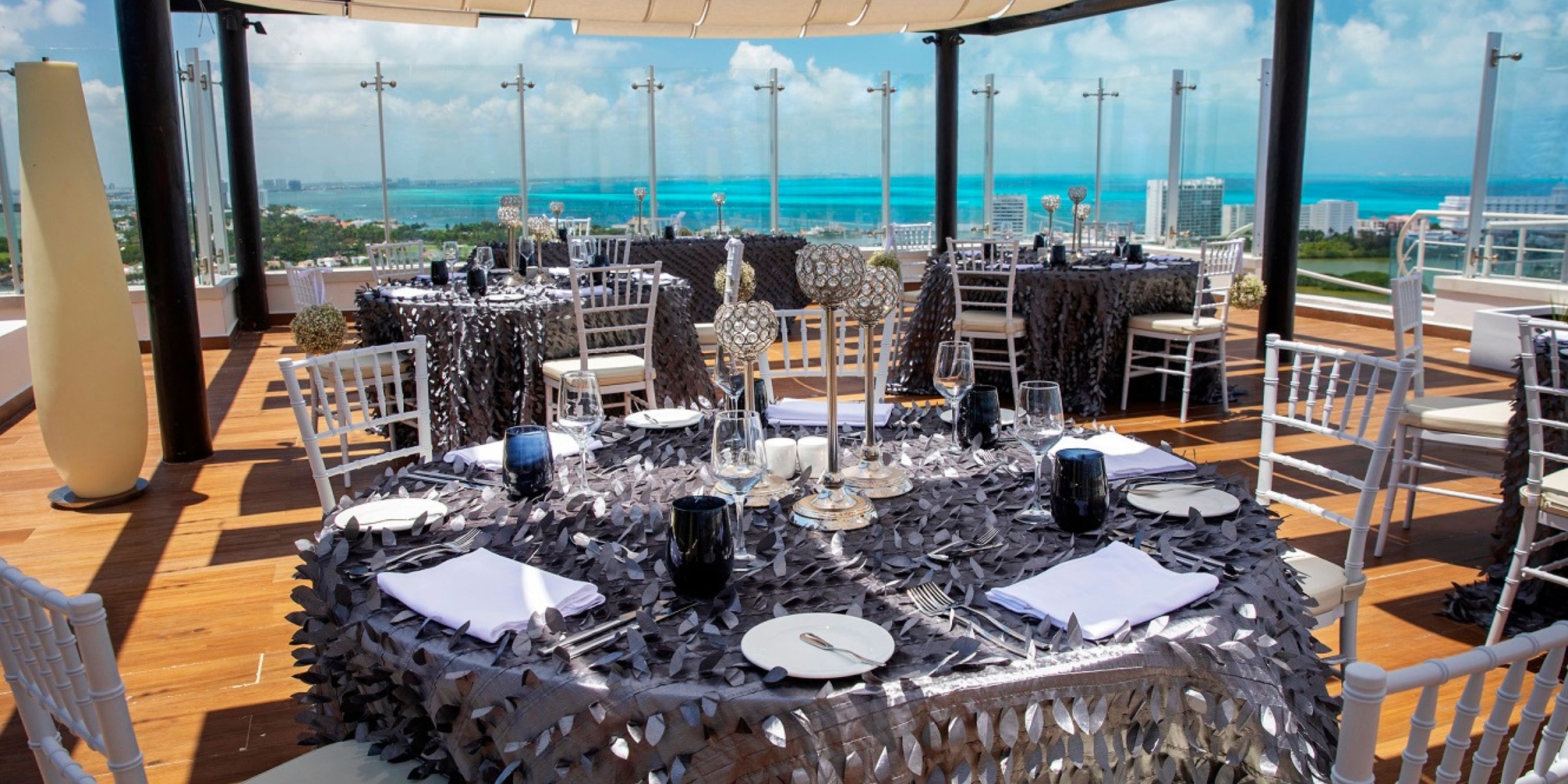 Experience an enchanting wedding dining setup at Royalton CHIC Suites Cancun, featuring elegant silver tablecloths and a breathtaking ocean view. Perfect for a destination wedding celebration.