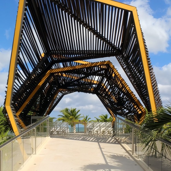 Geometric metal canopy over a walkway, perfect for a destination wedding, with palms and ocean behind.
