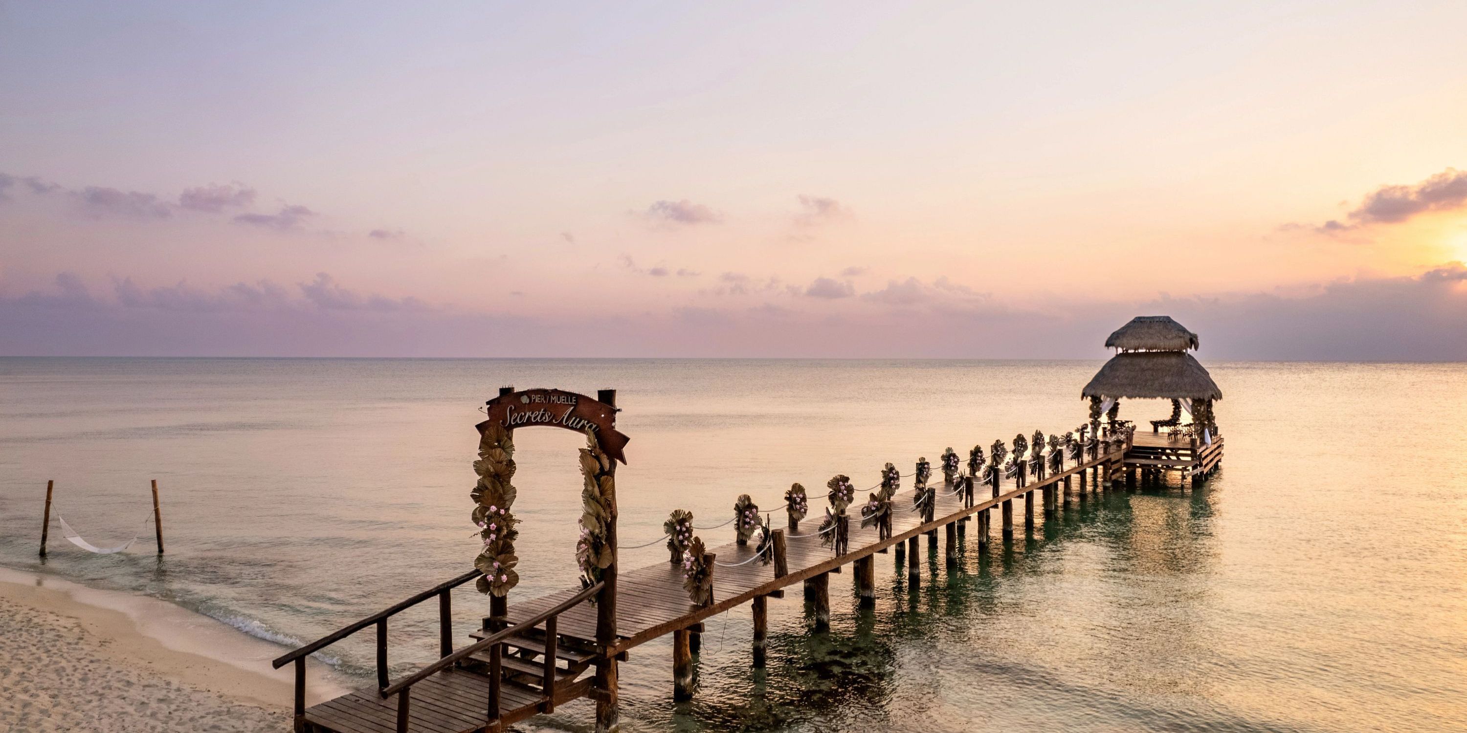 Secrets Aura Cozumel&rsquo;s pier with a thatched hut, perfect for a destination wedding at sunset.