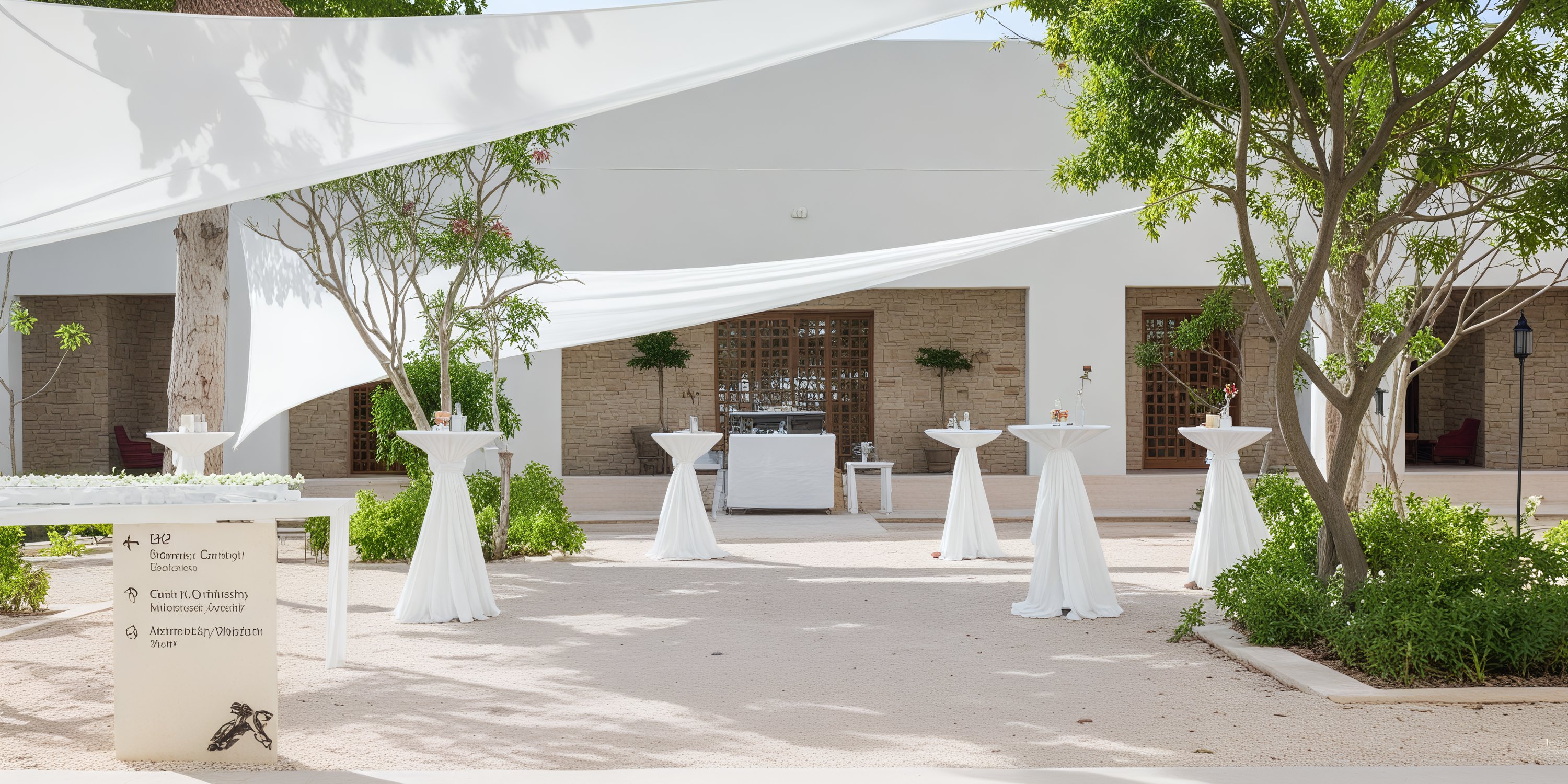 Secrets Akumal is an enchanting outdoor venue perfect for a destination wedding, featuring tall tables adorned with white drapes and surrounded by lush greenery under the vibrant blue skies.