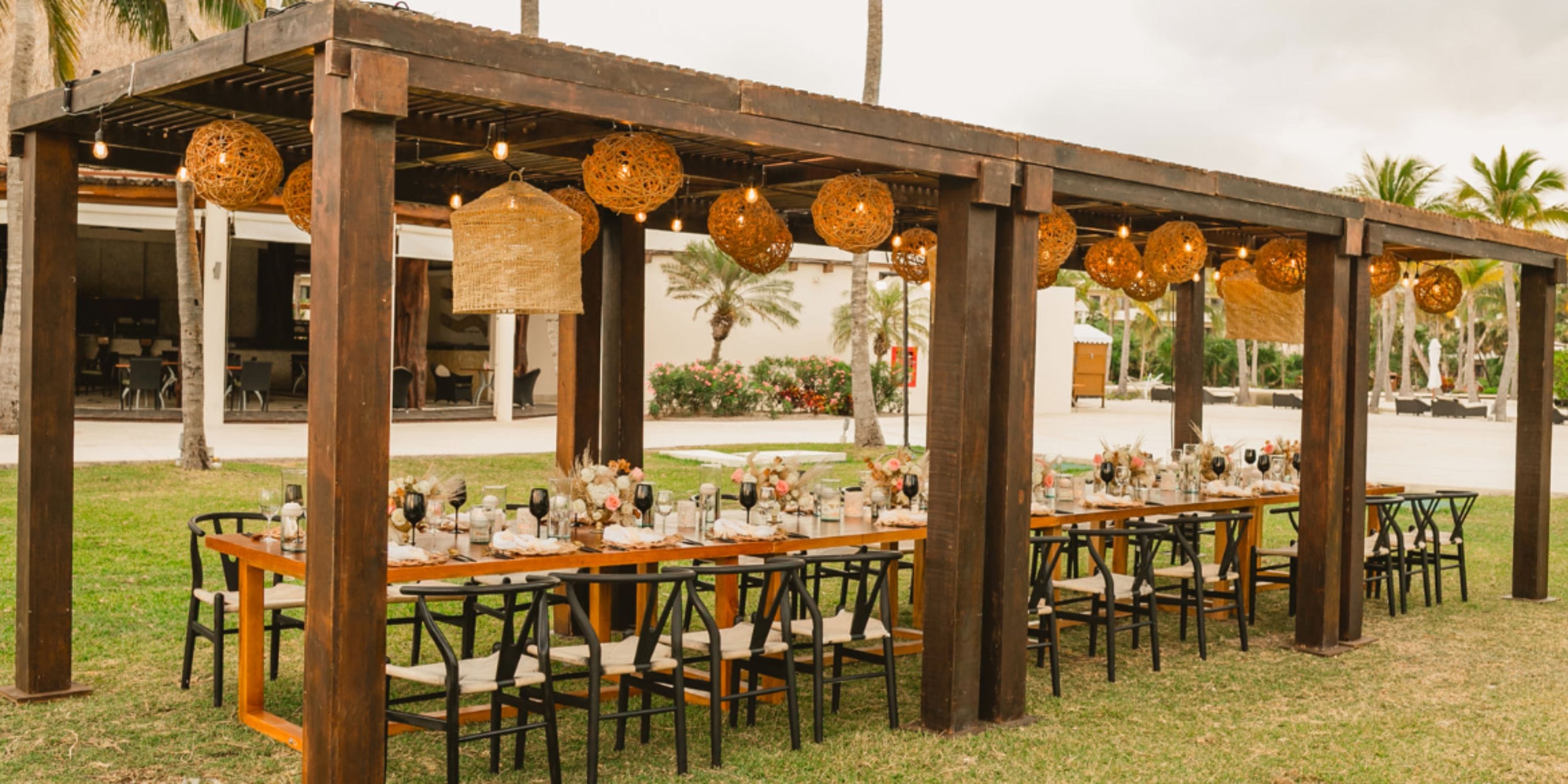 Wedding dining tables arranged under a pergola with hanging lights at Secrets Maroma Beach.