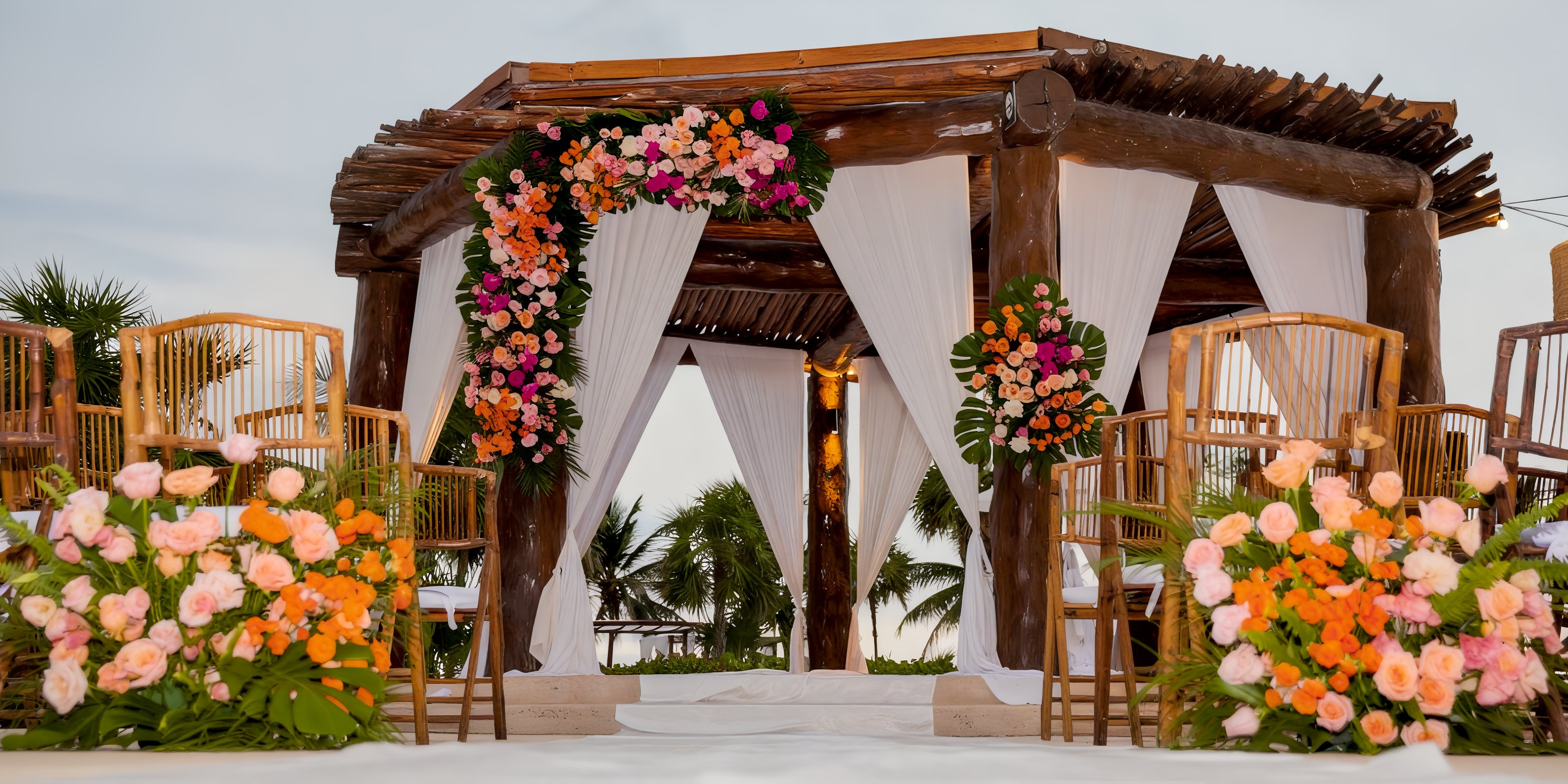 Gazebo at Secrets Maroma Beach with white drapes and flowers, set up for a destination wedding ceremony.