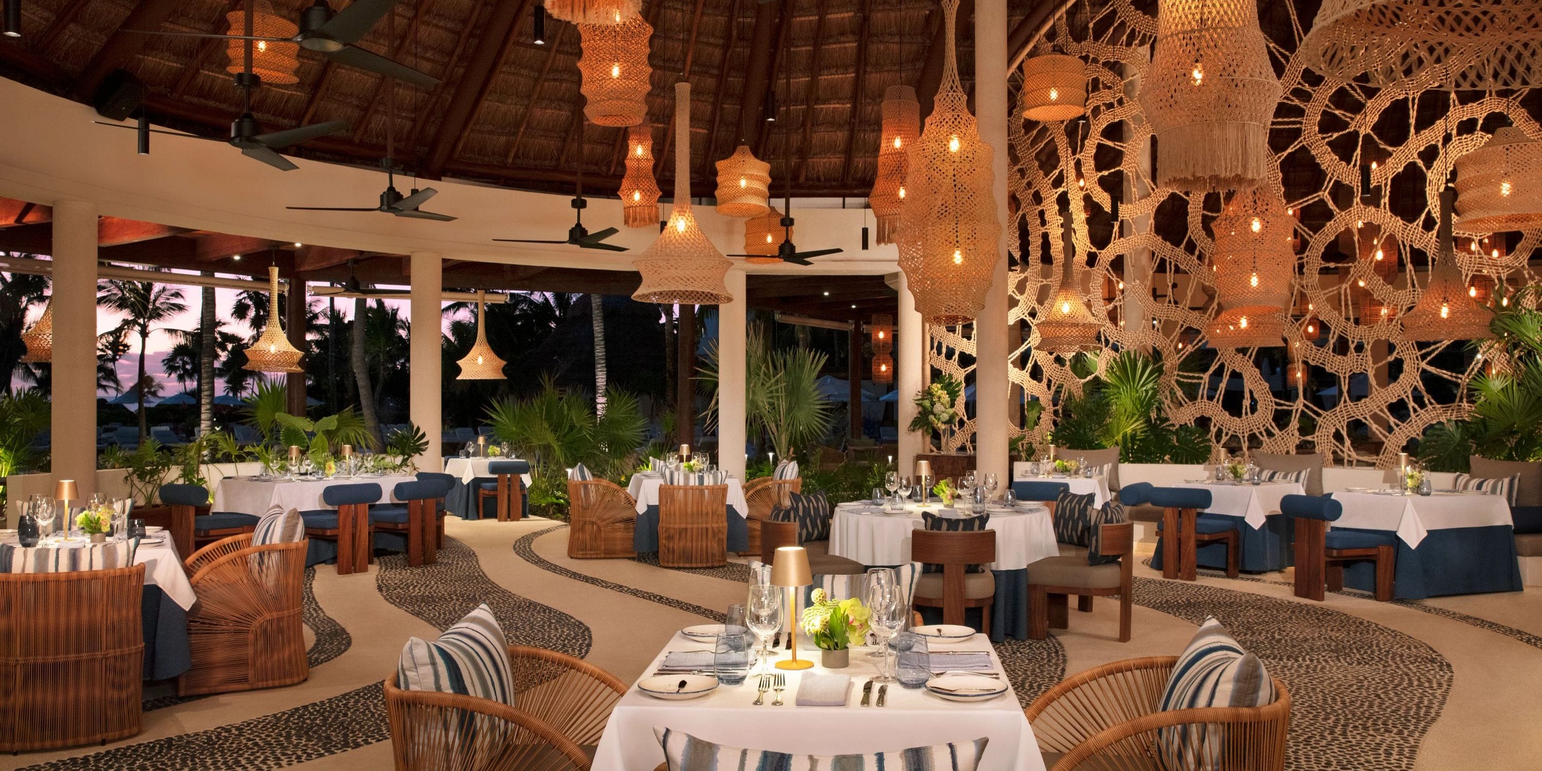 Secrets Maroma Beach: Elegant wedding venue with woven accents, blue chairs, and pendant lights.