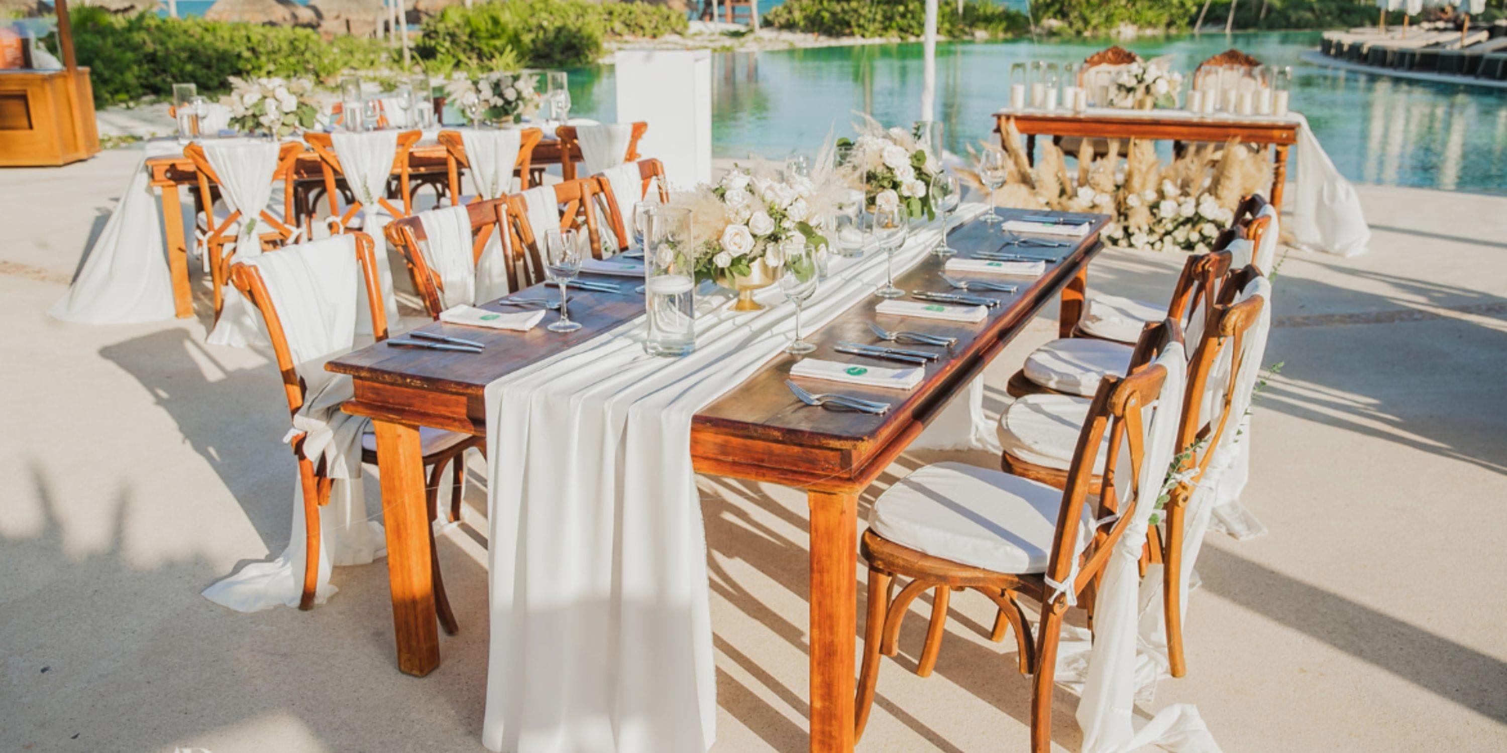 Destination wedding table at Secrets Maroma Beach with white linens, flowers, and poolside view.