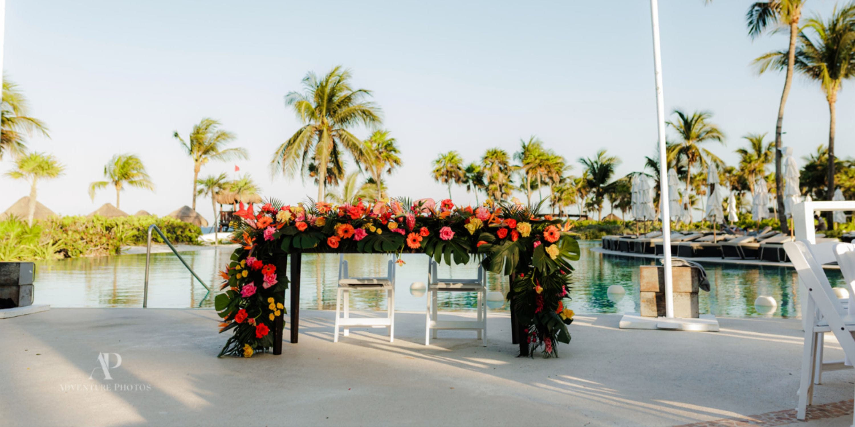 Secrets Maroma Beach: Poolside floral table, palms, and lounge chairs set for a destination wedding.