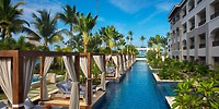 Poolside cabanas by a long pool at Secrets Royal Beach, ideal for a destination wedding amid palm trees.
