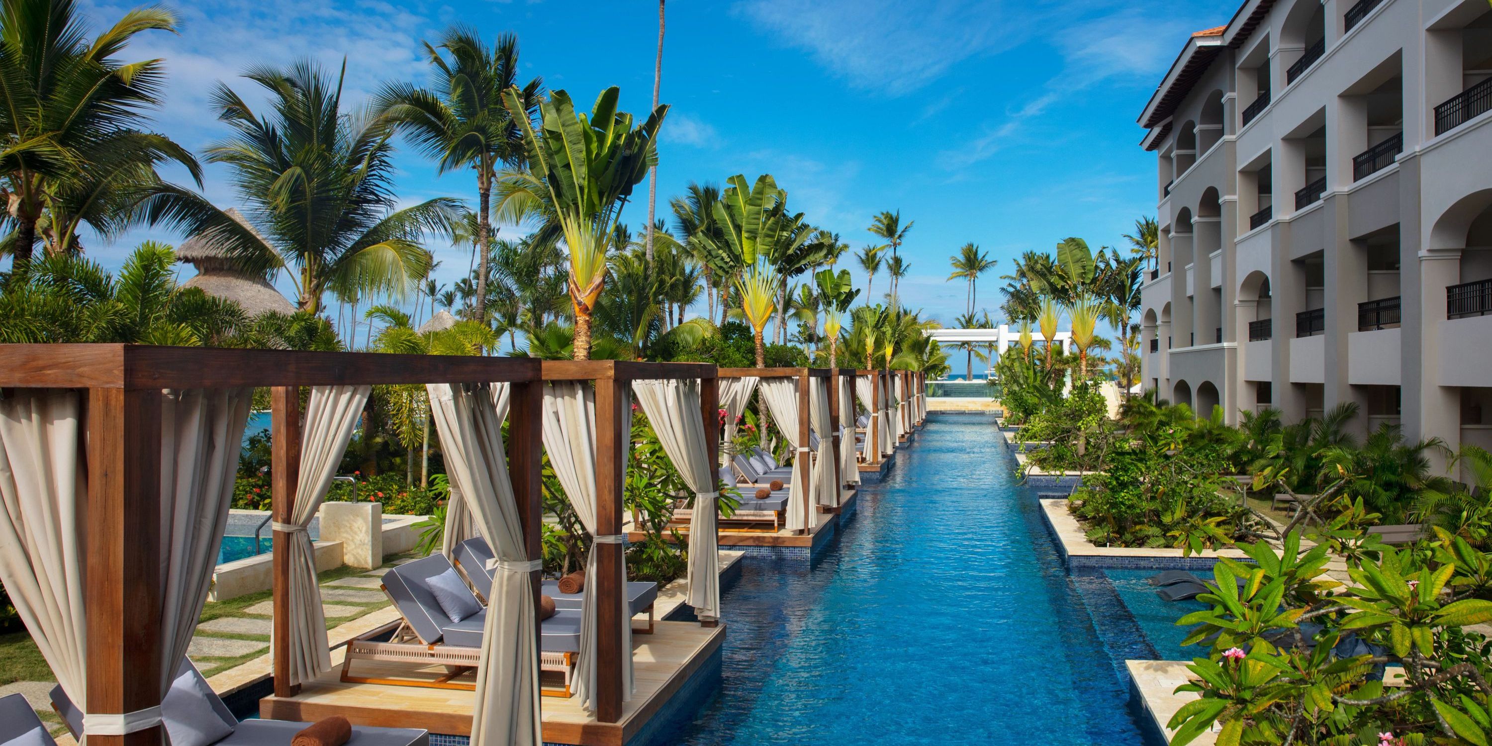 Poolside cabanas by a long pool at Secrets Royal Beach, ideal for a destination wedding amid palm trees.