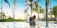 Couple smiling and embracing in the Secrets Royal Beach pool, celebrating their destination wedding.