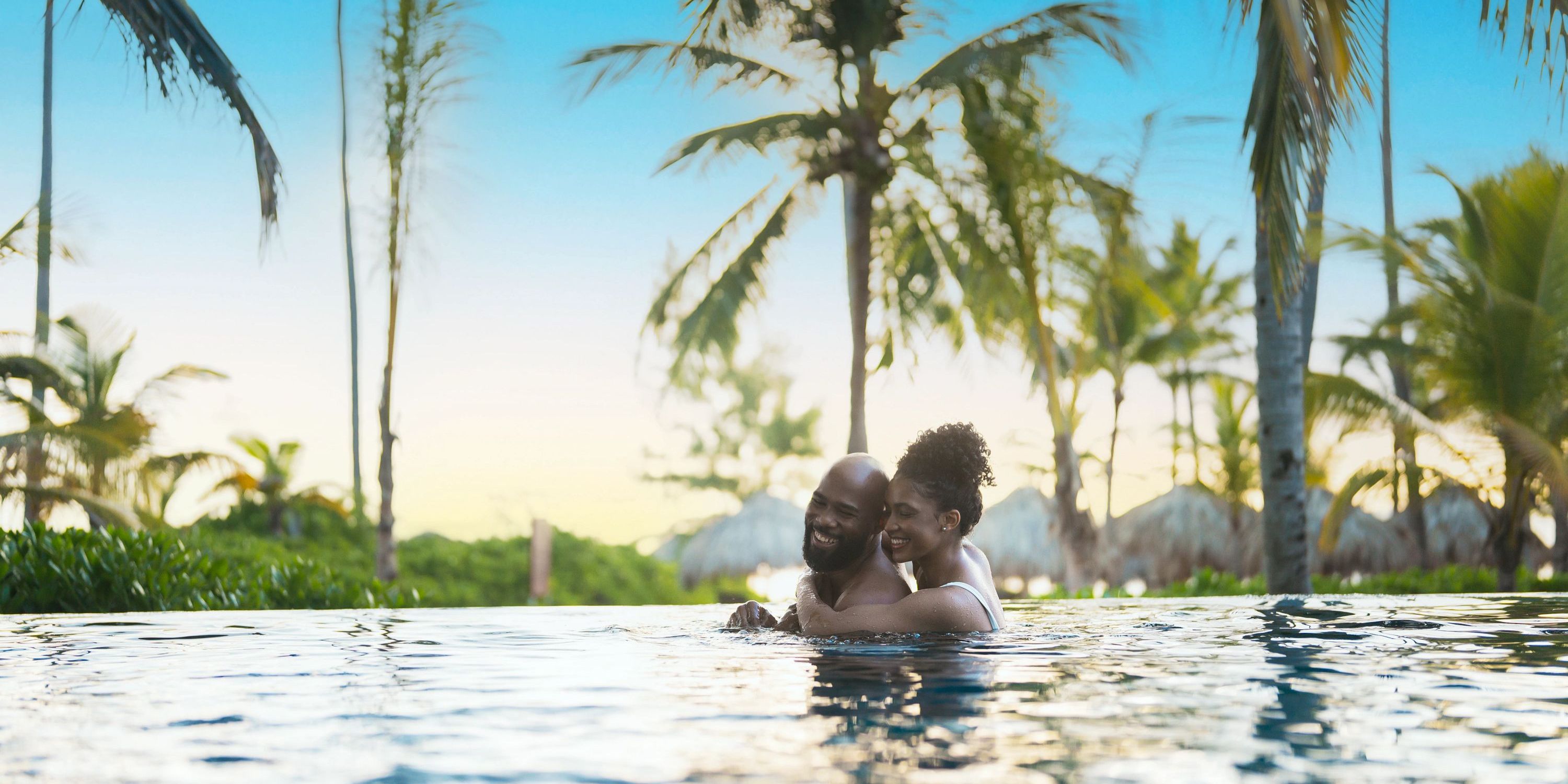 Couple smiling and embracing in the Secrets Royal Beach pool, celebrating their destination wedding.