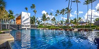 Secrets Royal Beach's modern pool area with lounge chairs and umbrellas is ideal for a destination wedding.