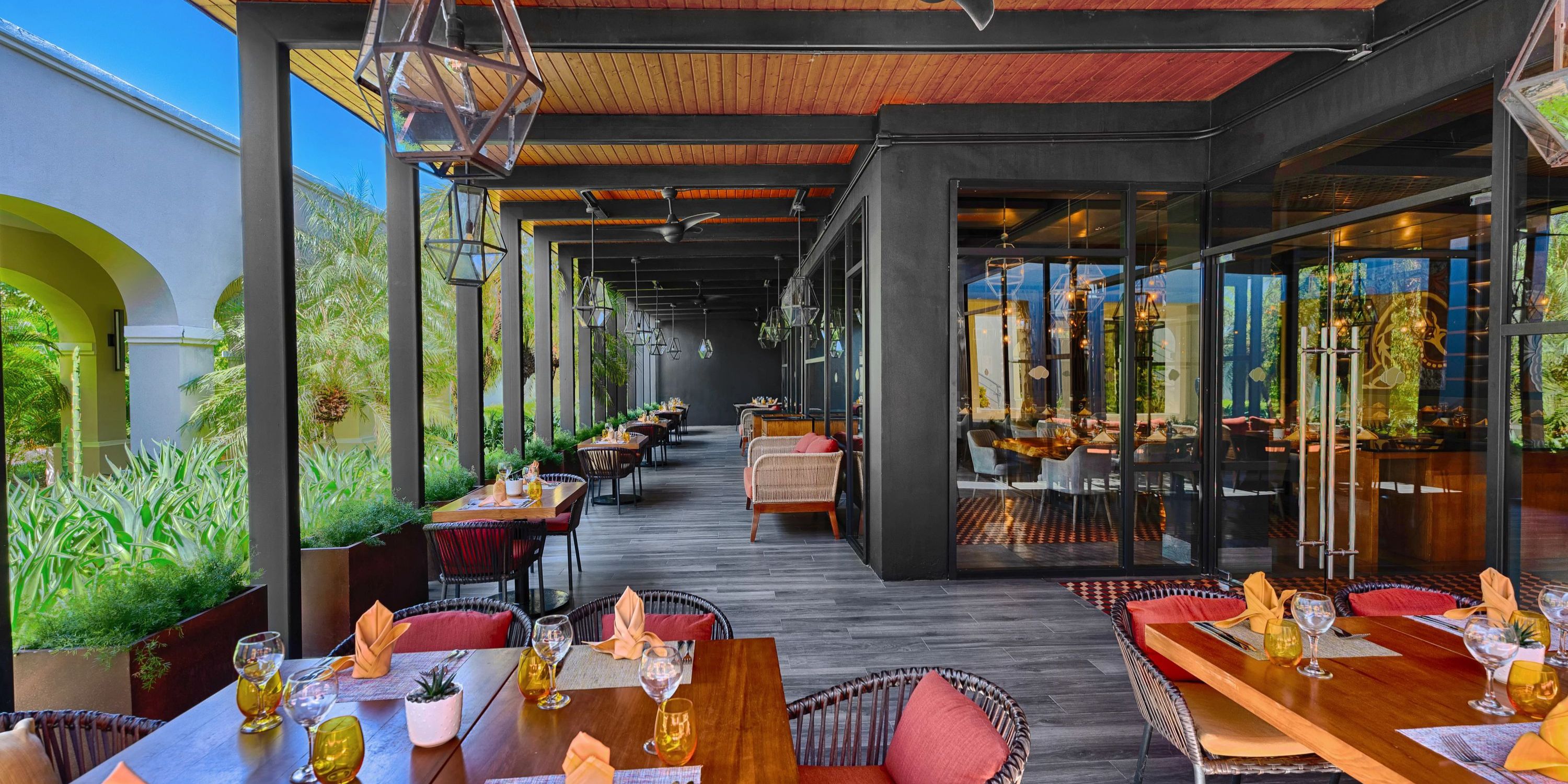 Secrets Royal Beach patio, perfect for a destination wedding, with wooden tables and cushioned chairs.