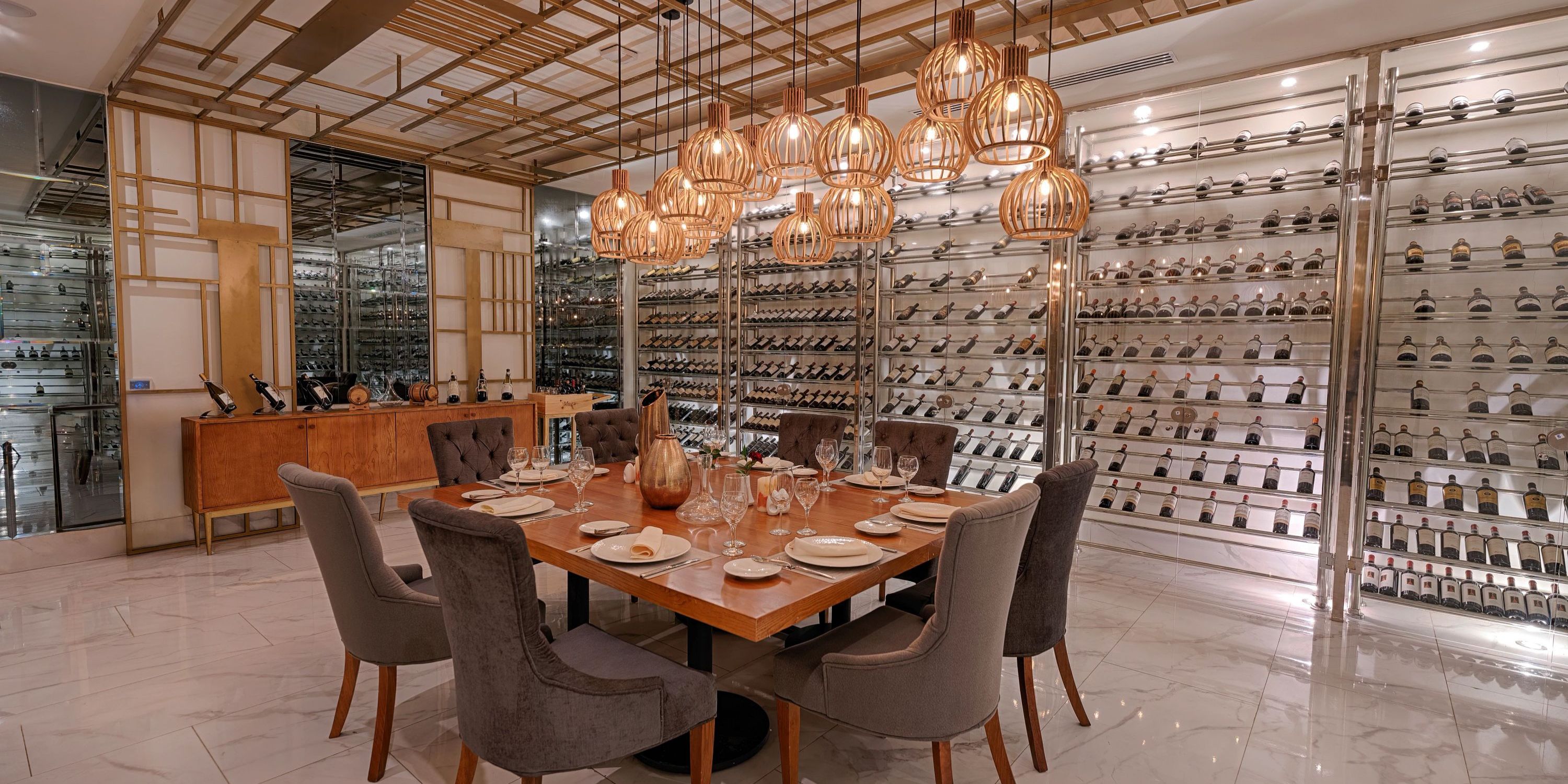 Chic destination wedding dining at Secrets Royal Beach, set table, modern lights, and wine wall backdrop.