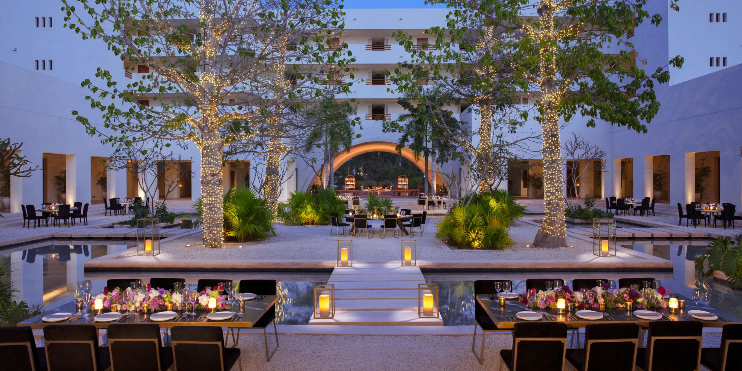 Outdoor venue Plaza Akumal with pool and lights, set up for a destination wedding ceremony