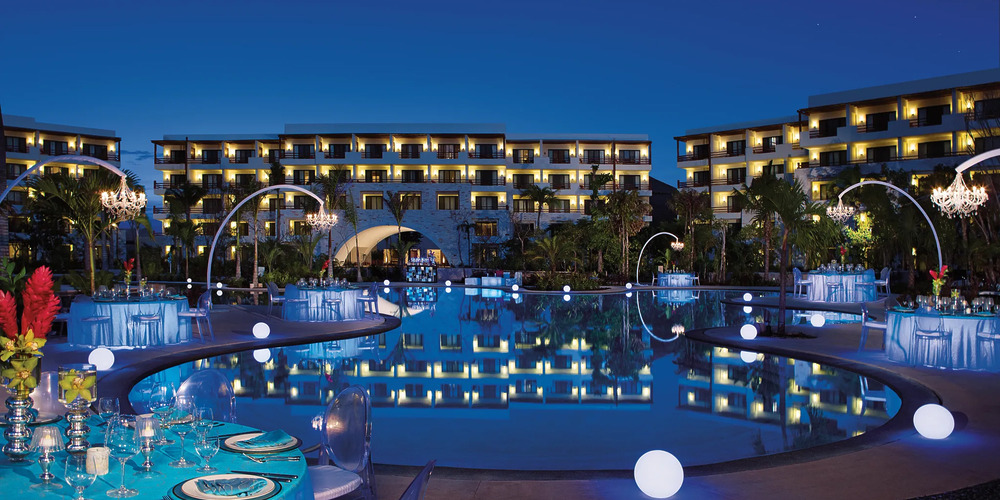 Nighttime by the pool, reflecting the lights from the resort in the background