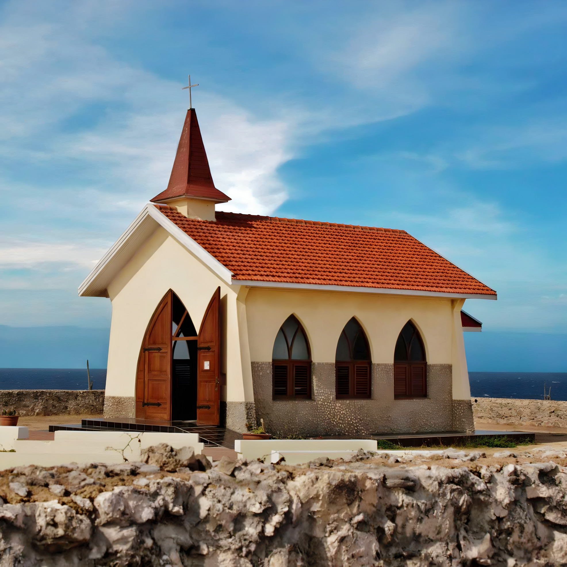 A small white church with a red roof, perfect for destination weddings, located by the sea under a cloudy sky.