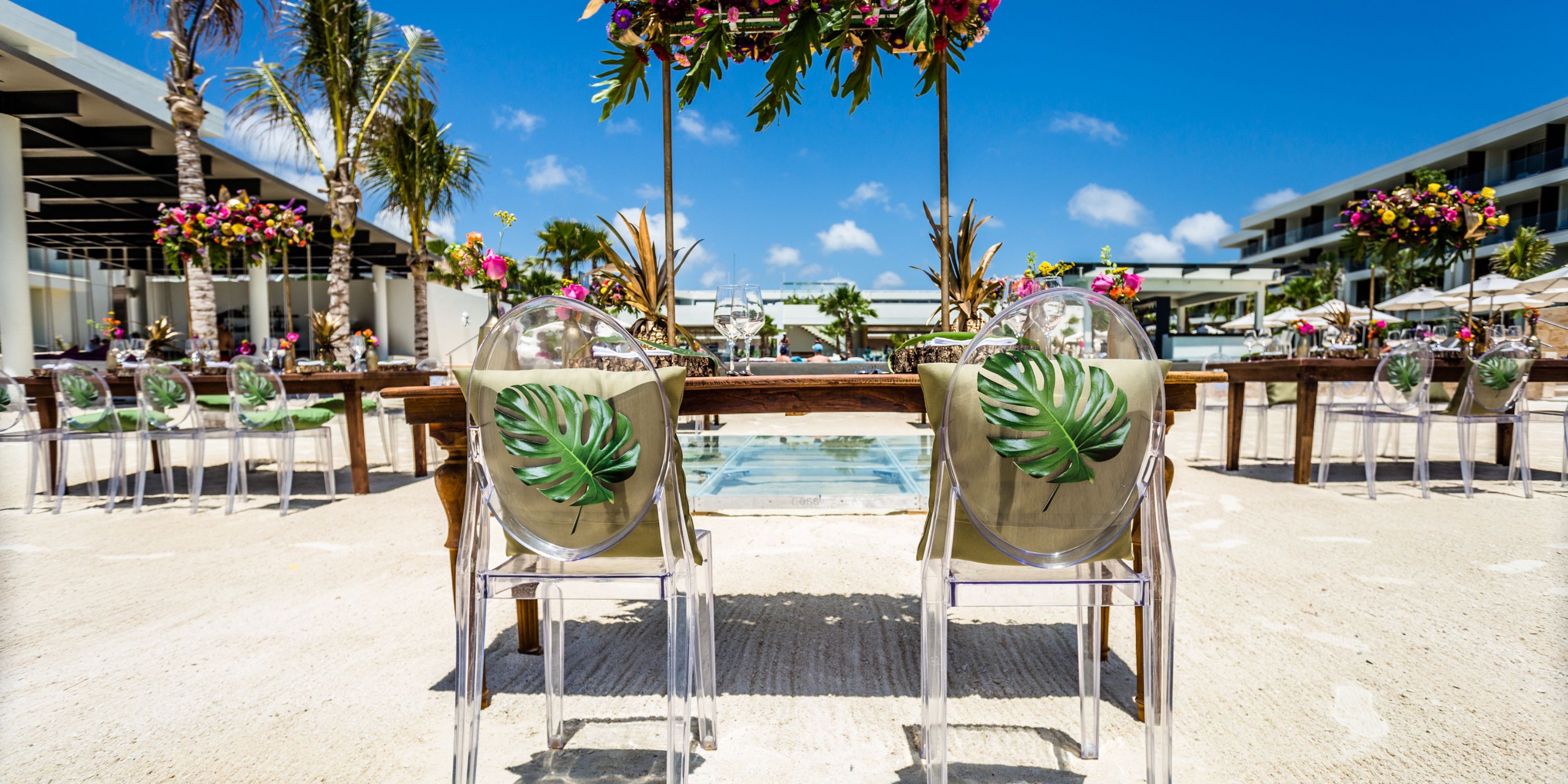 Two chairs with leaf decor at a Secrets Riviera Cancun destination wedding, poolside with floral accents.