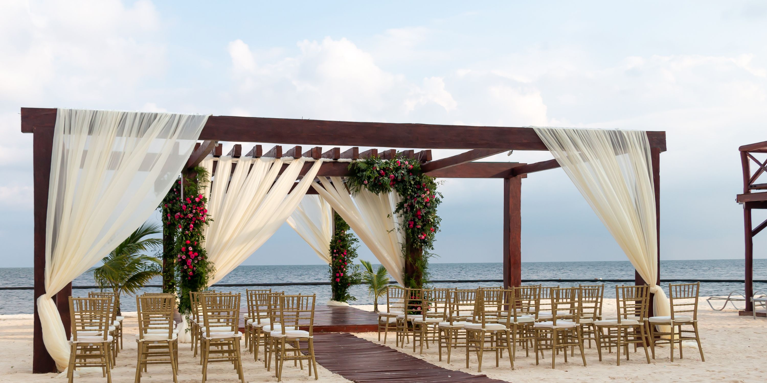 Destination wedding setup at Secrets Riviera Cancun with elegant drapes, chairs, and floral decorations.