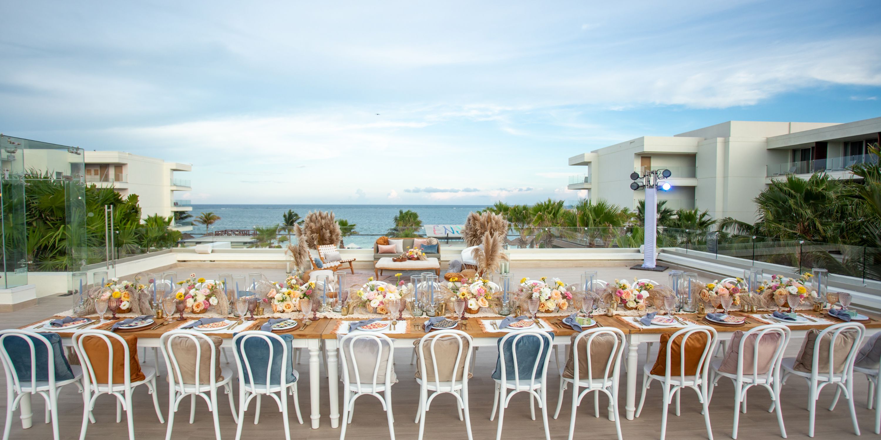 Long table set for a destination wedding at Secrets Riviera Cancun, overlooking the ocean and city.