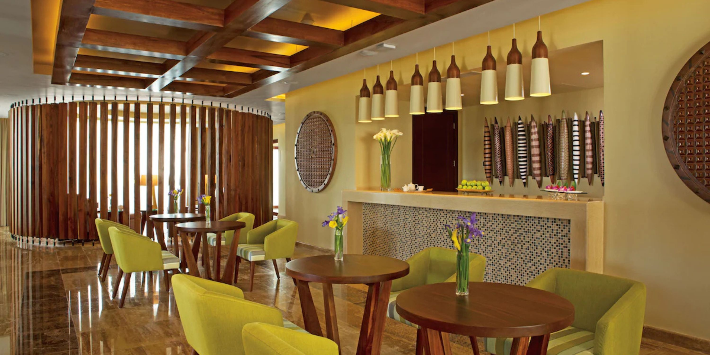 Chic lounge at Secrets Playa Mujeres, perfect for destination weddings, with green chairs and wood tables.