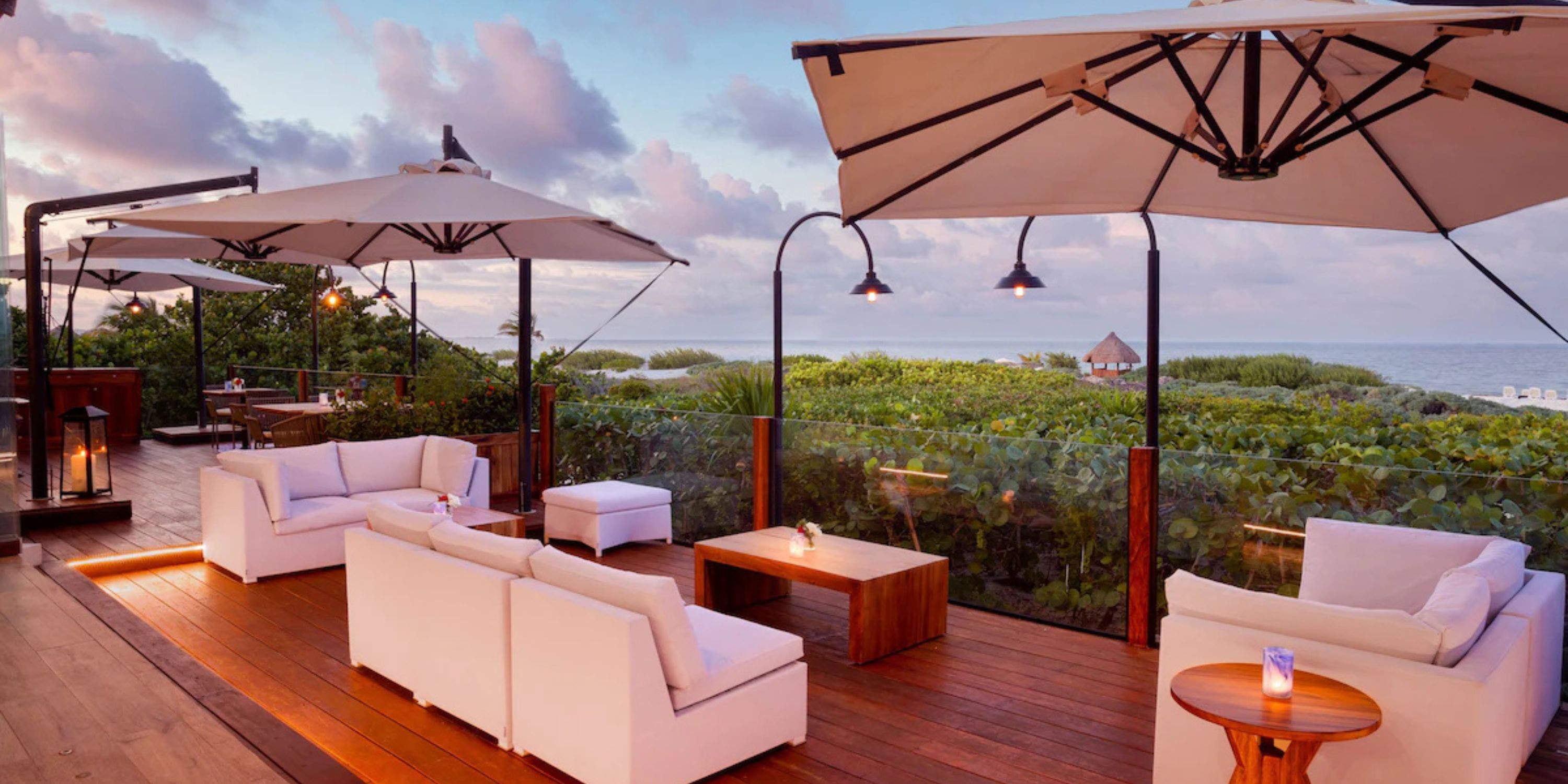 Secrets Playa Mujeres patio with white sofas and ocean view at sunset, perfect for a destination wedding.