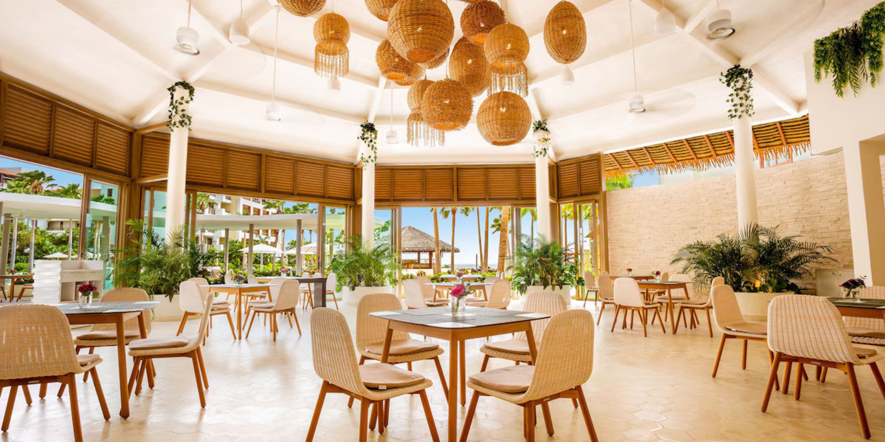 Secrets Playa Mujeres offers open-air dining with wicker chairs and large hanging lights for a wedding.