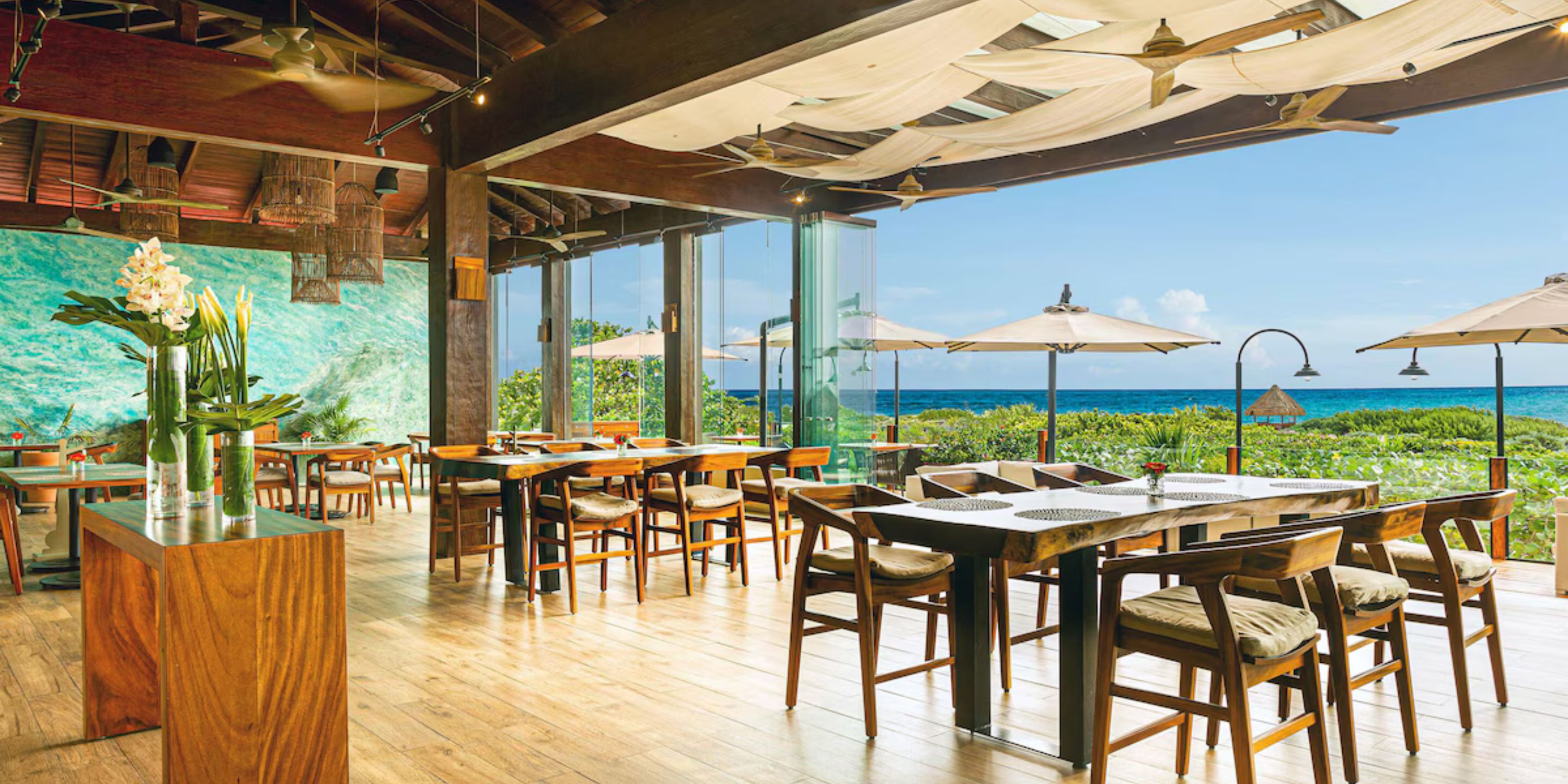 Secrets Playa Mujeres features ocean views, wooden tables, and a patio with umbrellas for destination weddings.