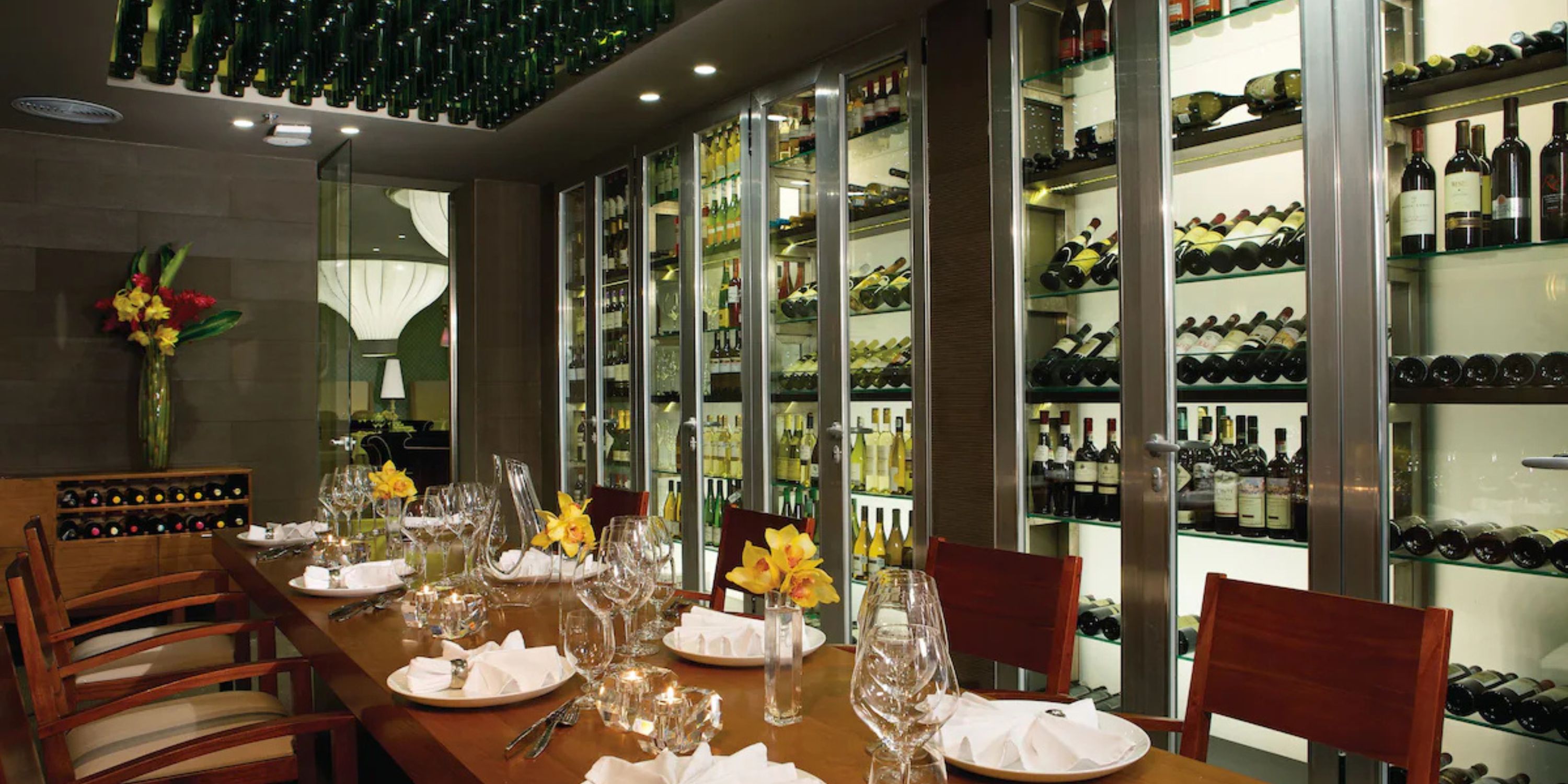 Secrets Playa Mujeres: Elegant wedding dining table surrounded by wine bottles and glassware shelving.