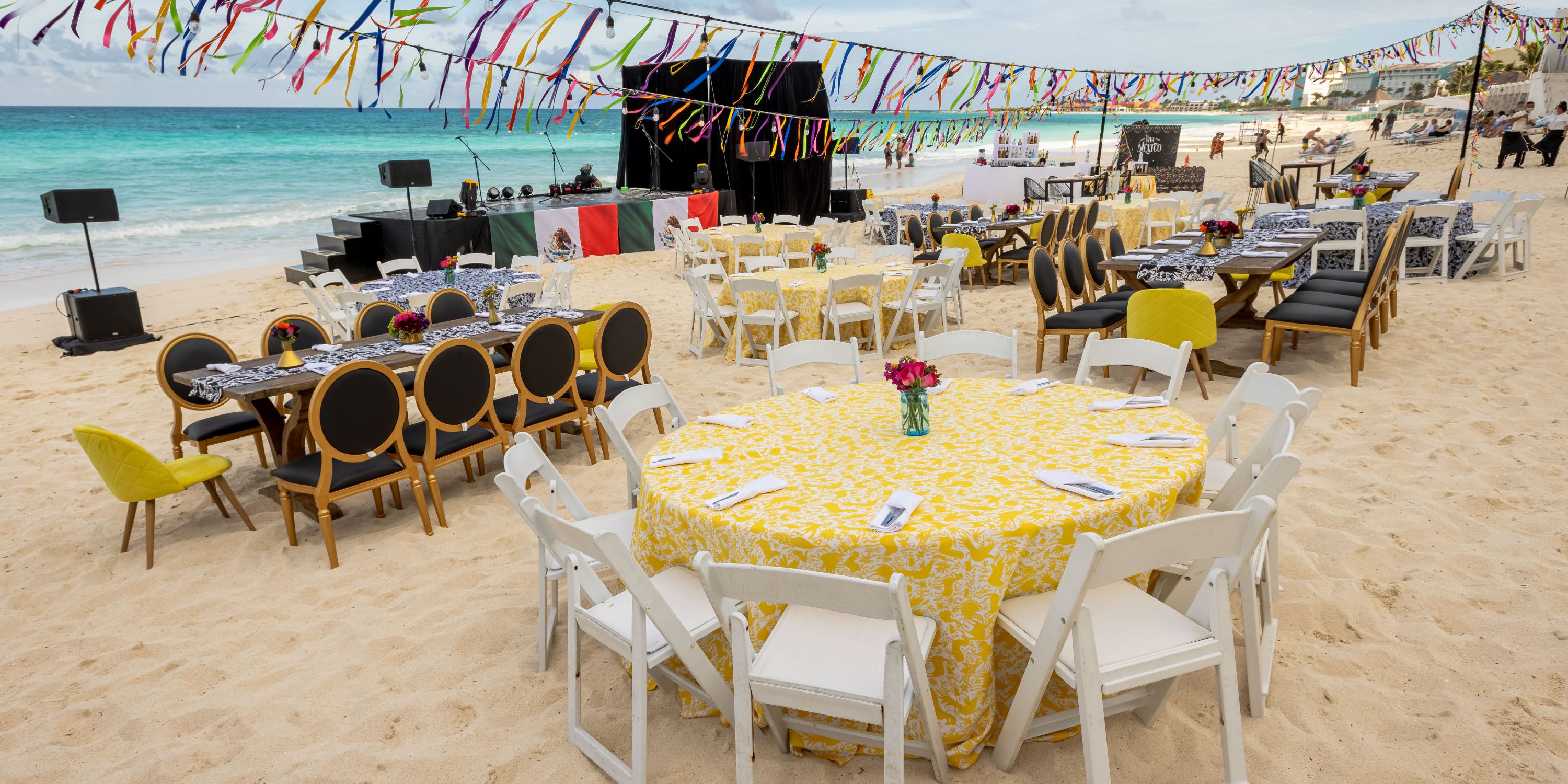Tables and chairs arranged for a destination wedding at Playacar Palace, with colorful ribbons hung above.