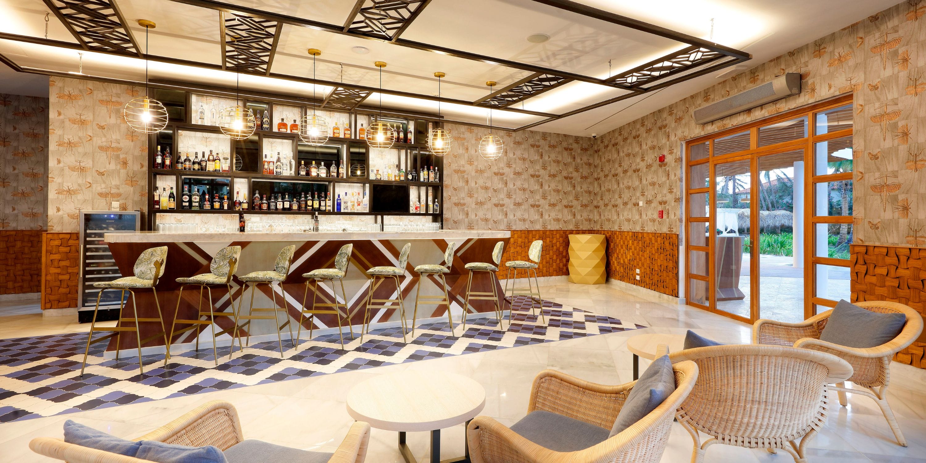 TRS Turquesa: Sleek indoor bar ideal for destination weddings, with high chairs and wicker lounge seats.